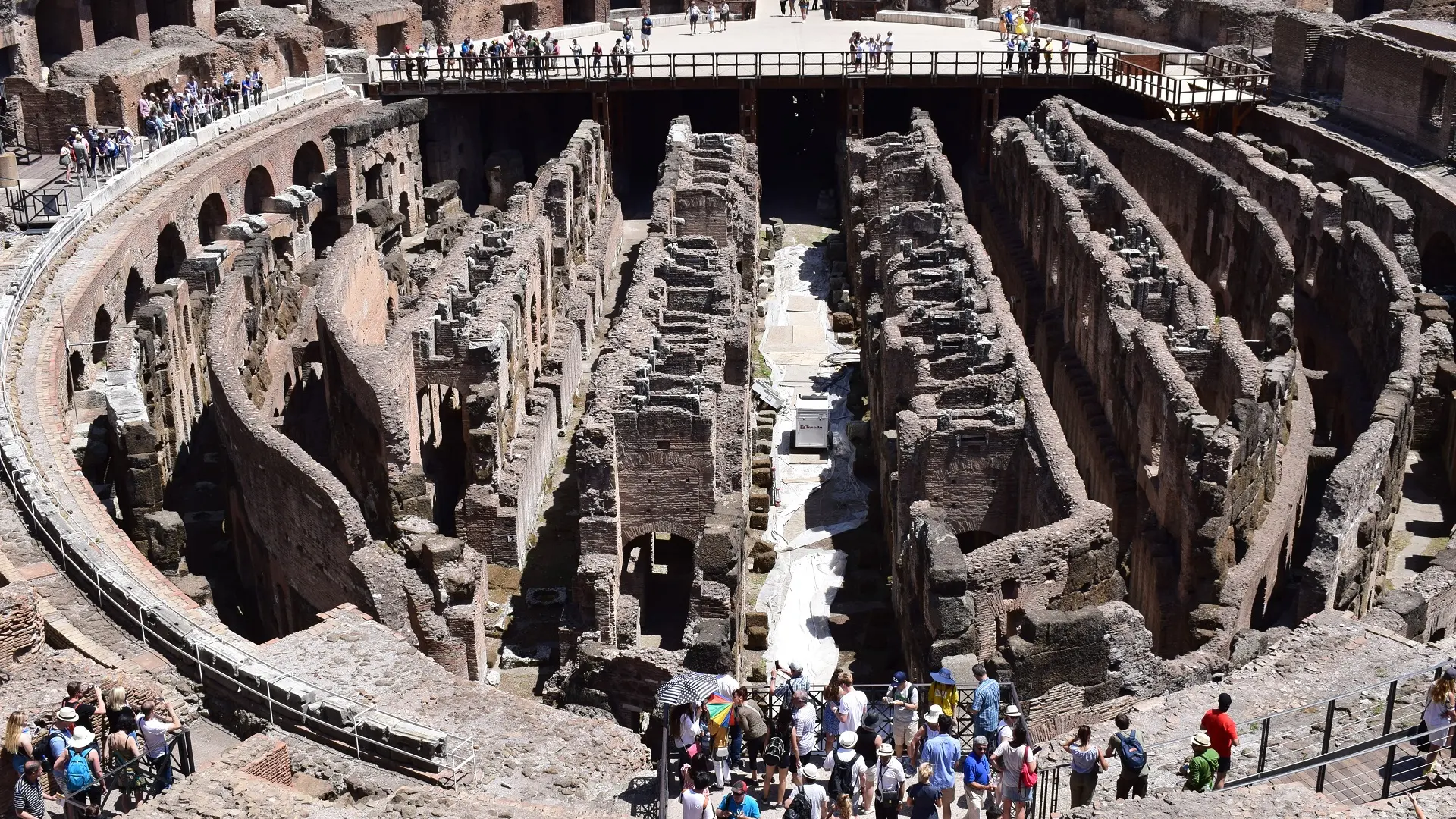 "Image depicting the subterranean passageways beneath the Colosseum, where the wooden stage once stood. The intricate network of tunnels and chambers is visible, highlighting the engineering marvel of ancient Rome, with dim lighting creating a mysterious atmosphere."