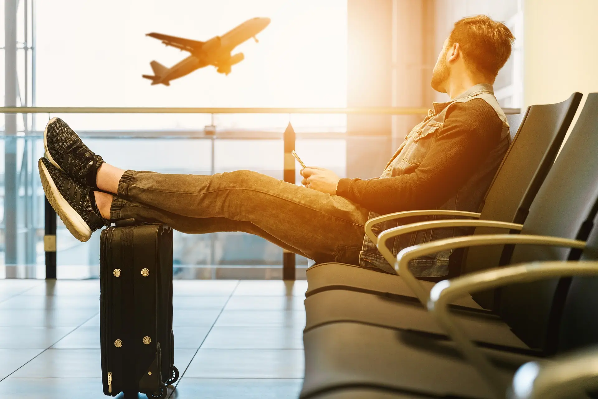 Man lading back in a chair with his feet on his luggage