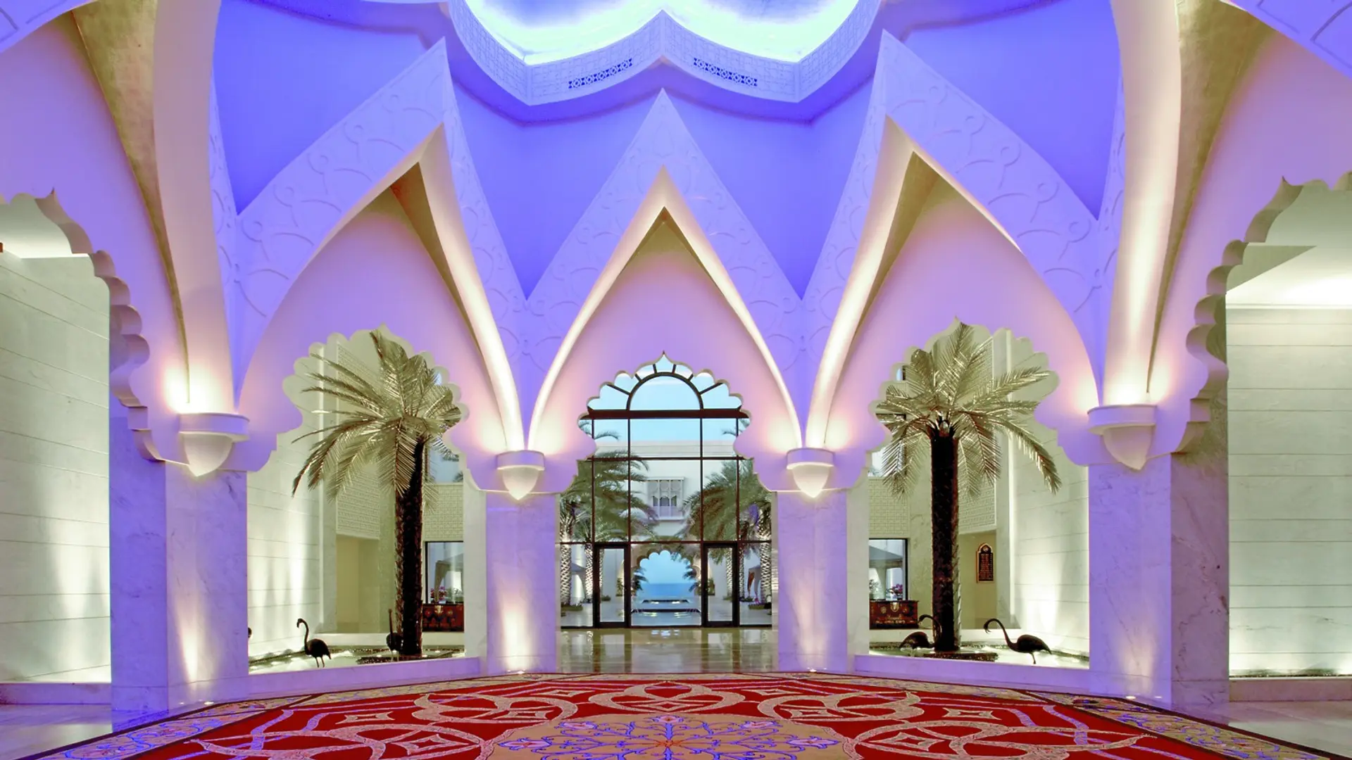 Red, yellow and blue pattern floor with flowers in the median, tall white marble walls and a view to the ocean