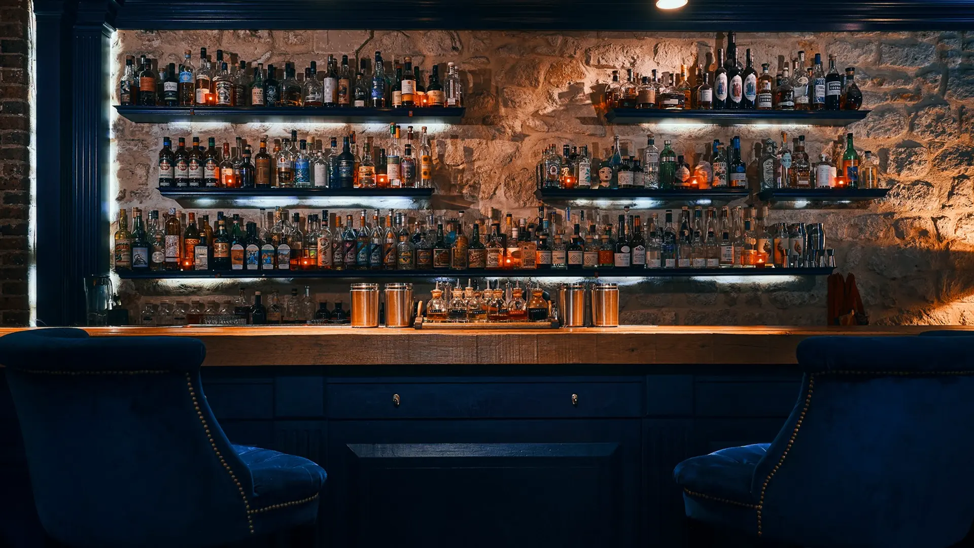 Navy blue chairs, wooden desk, and a lot of cocktail beverages in the backround.