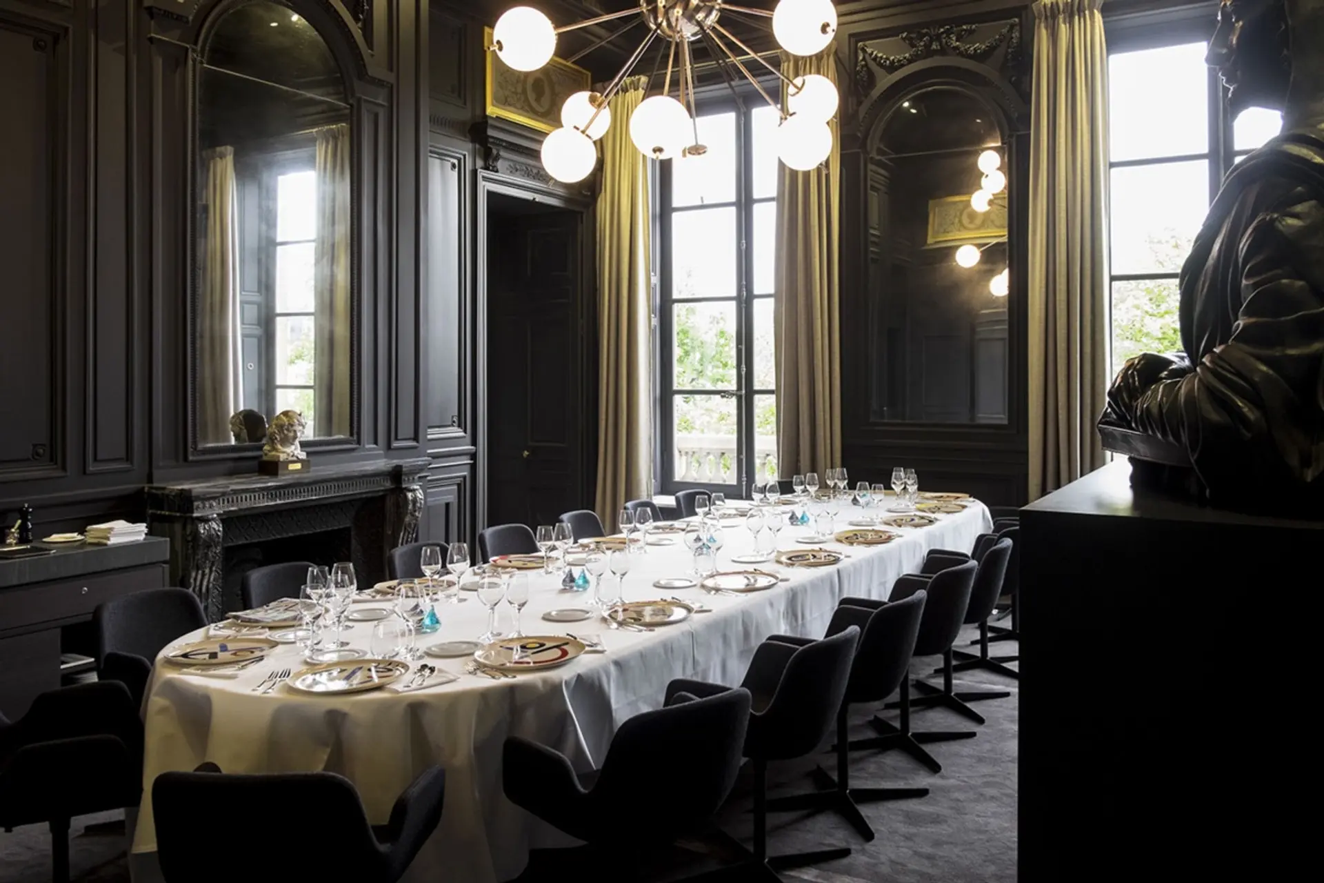 Big oval table with black chairs and black walls at guy savoy paris