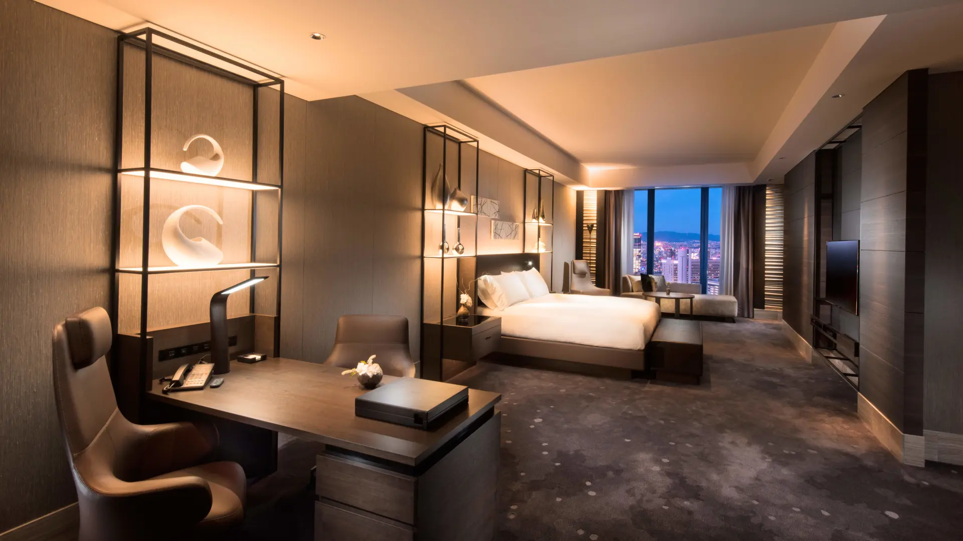 Hotel room with dark decor, windows to Osaka, work desk and flatscreen tv at Conrad Osaka.