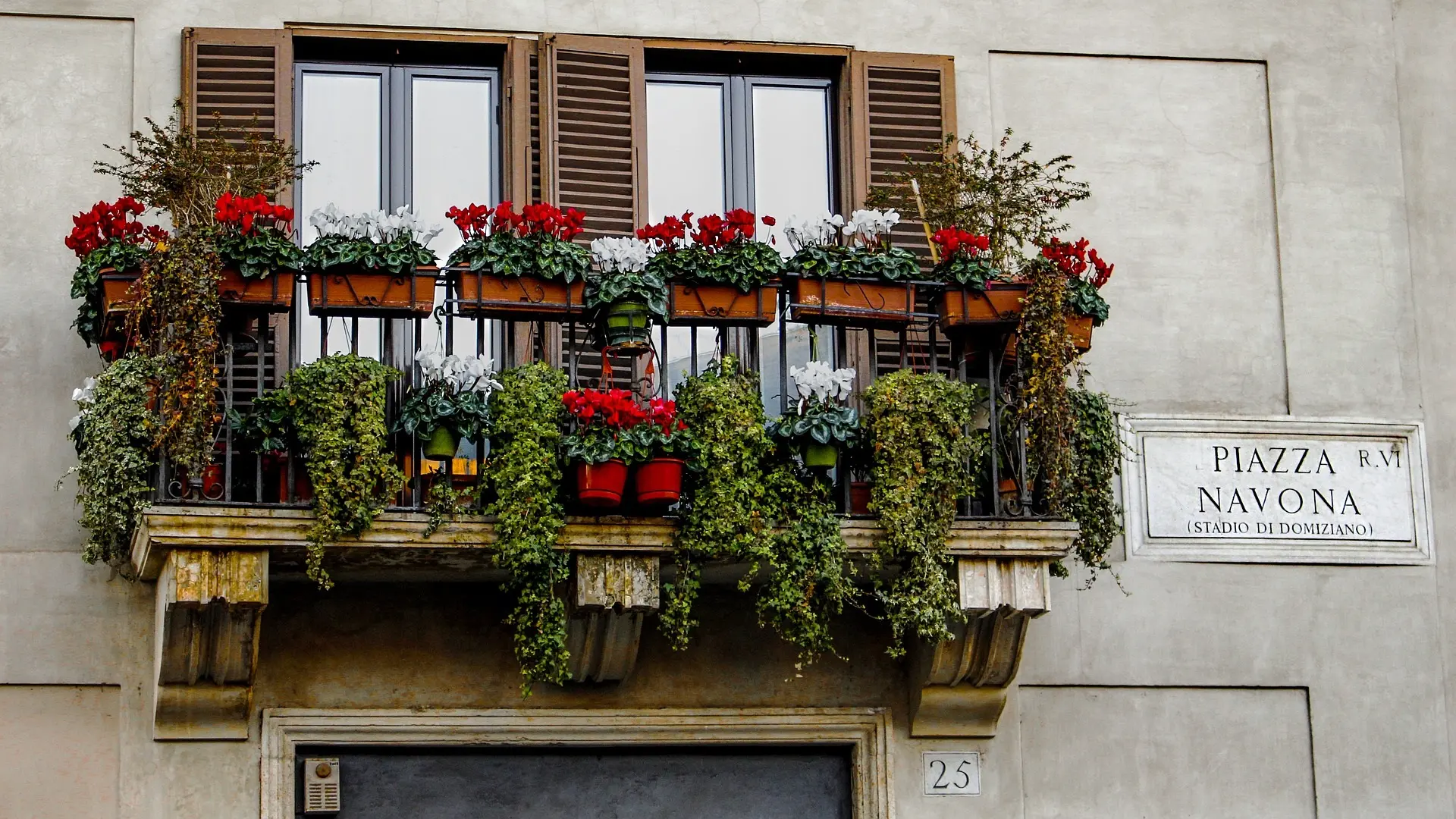 Iconic building with a private terrace feautering roses and plants with a sign saying PIAZZA NAVONA (STADIO DI DOMIZIANO)