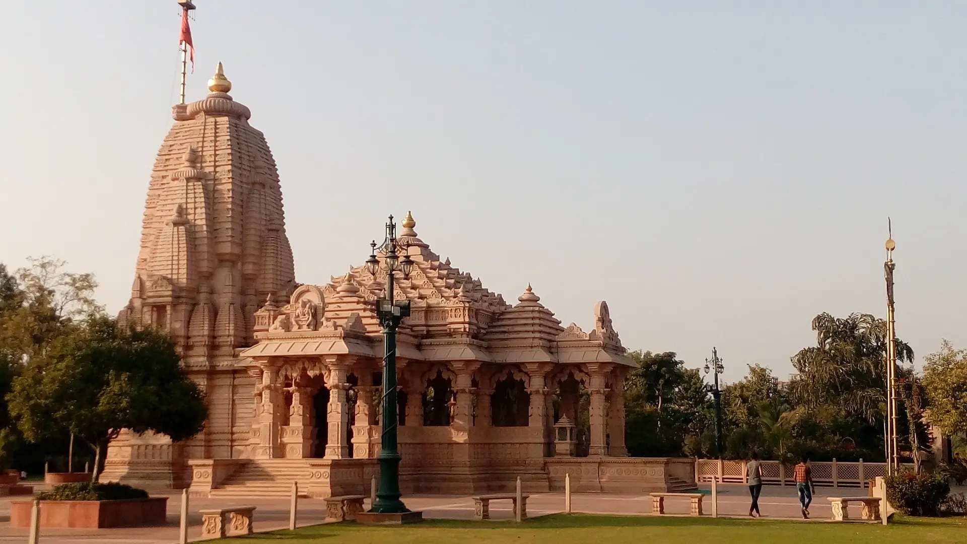 Afternoon time of the Sarvatobhadra Garbhgriha a large sand coloured building surrounded by trees.