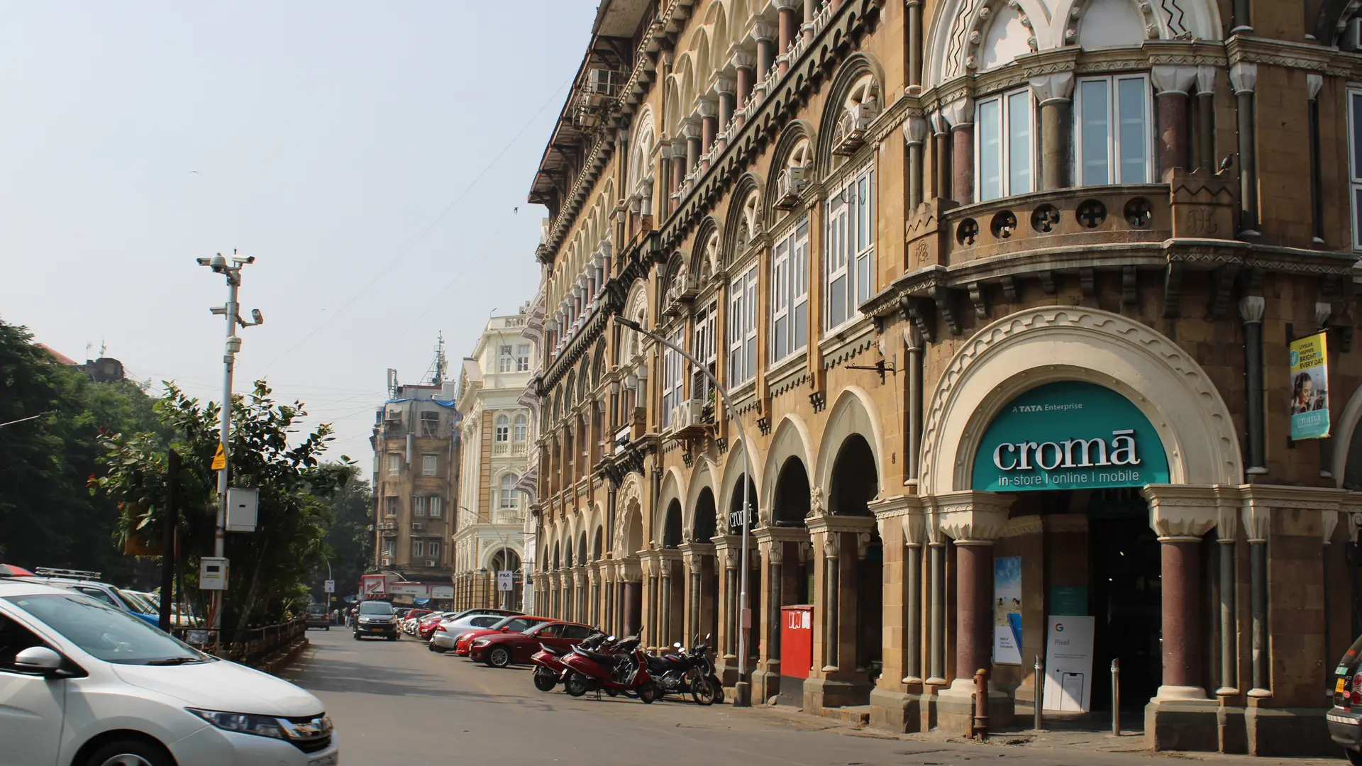Street with cars, and a classic building with white text saying: CROMA.