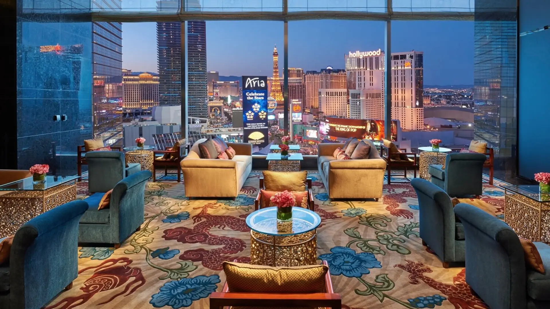 Lounge with rose carpet in beige, red and blue, seatings and furniture in blue and beige and a giant view to the city.