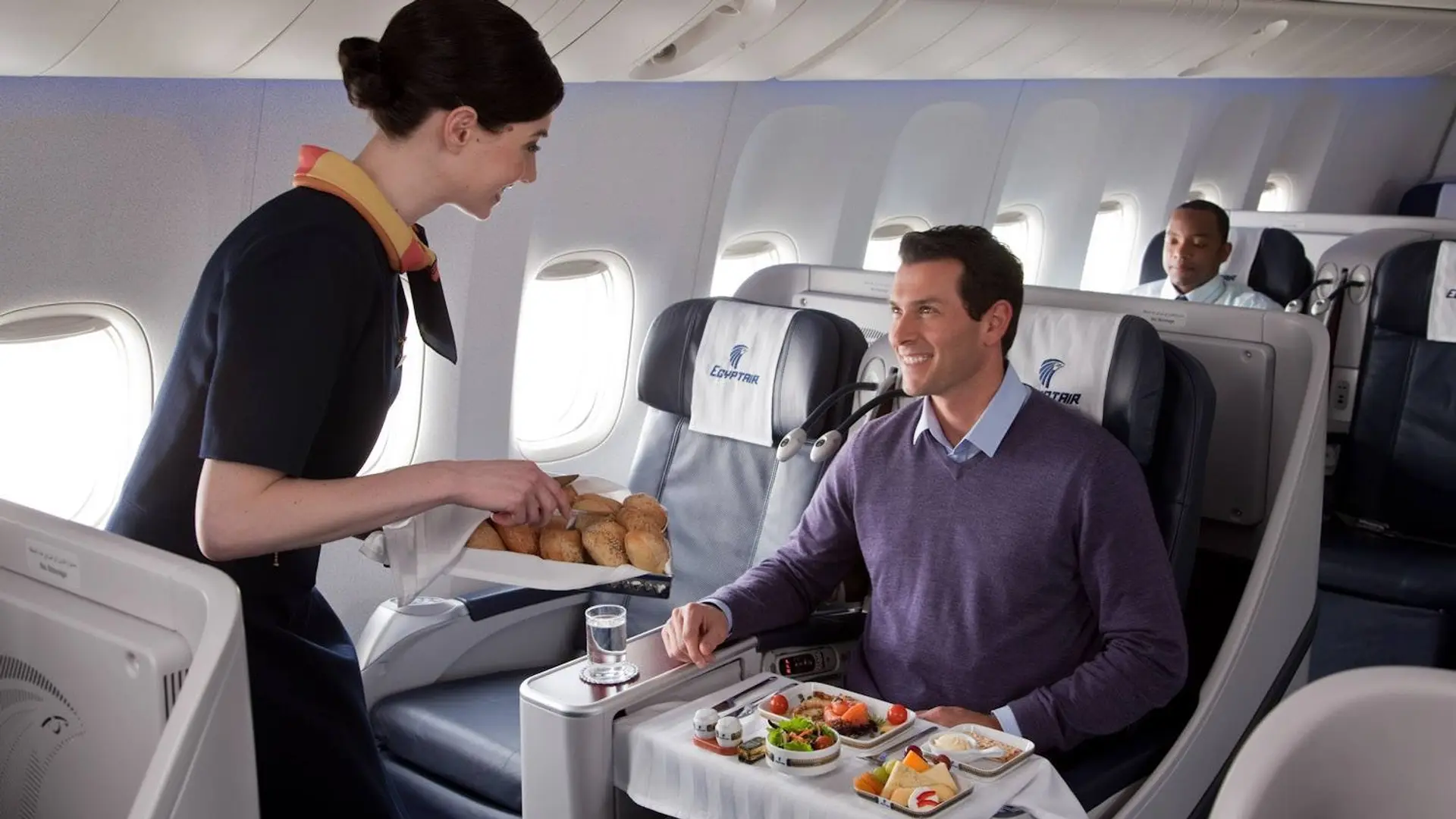 air hostess serving bread to a man in egypt air business class