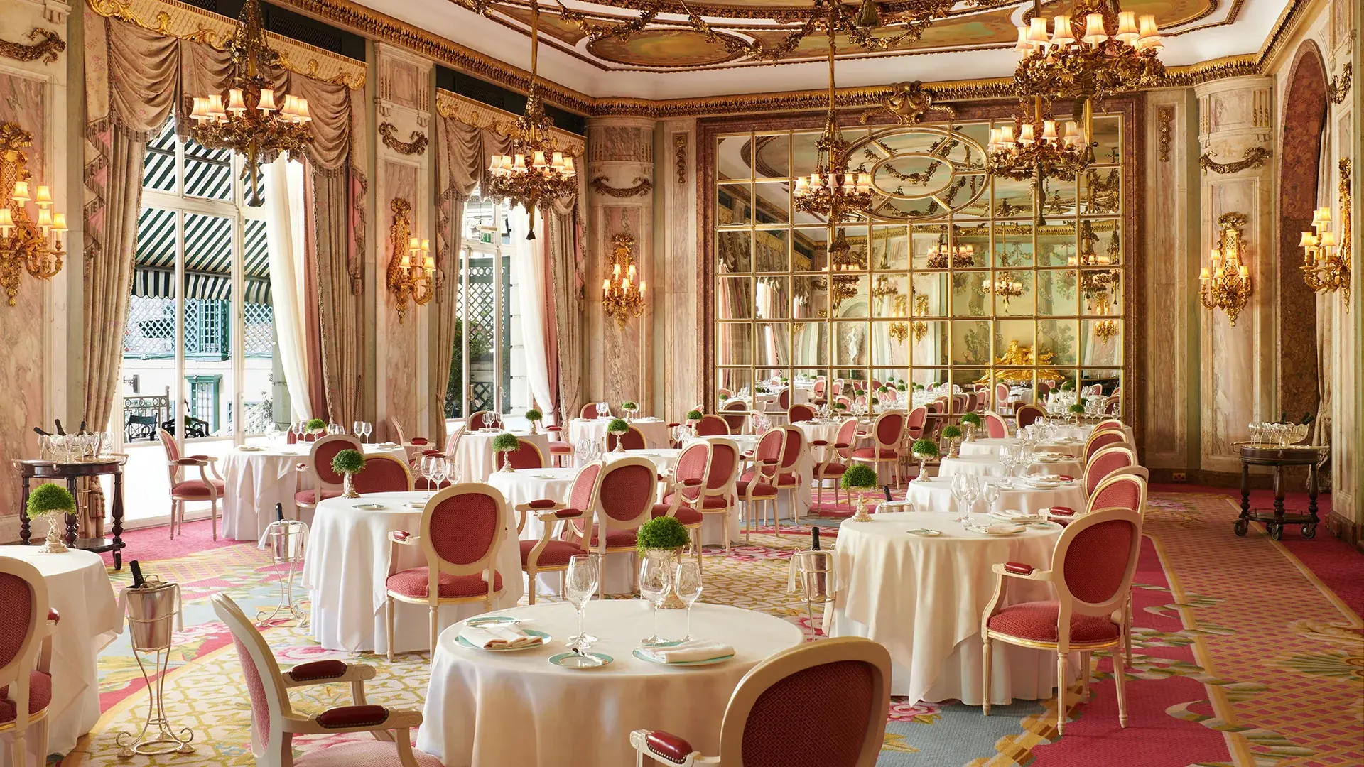 resturant at the ritz london with pink chairs, and large pink curtains.
