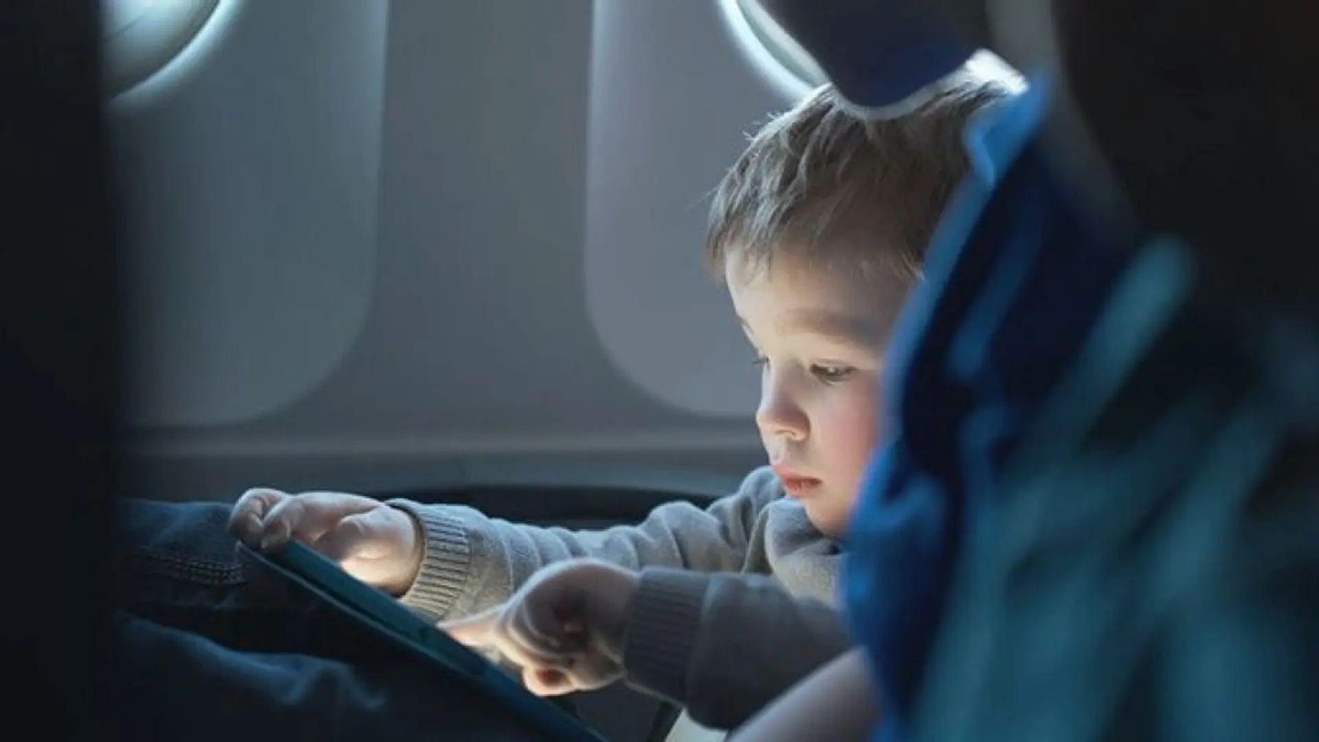 a toddler with his screen in business class
