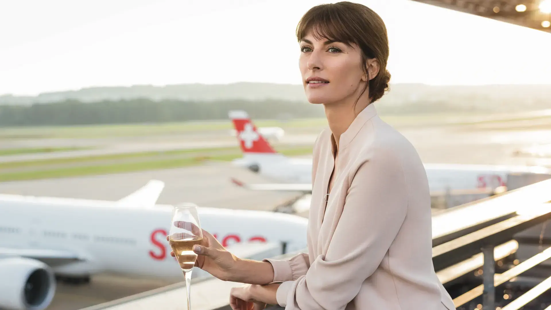 woman holding champagne ready to board SWISS First Class 