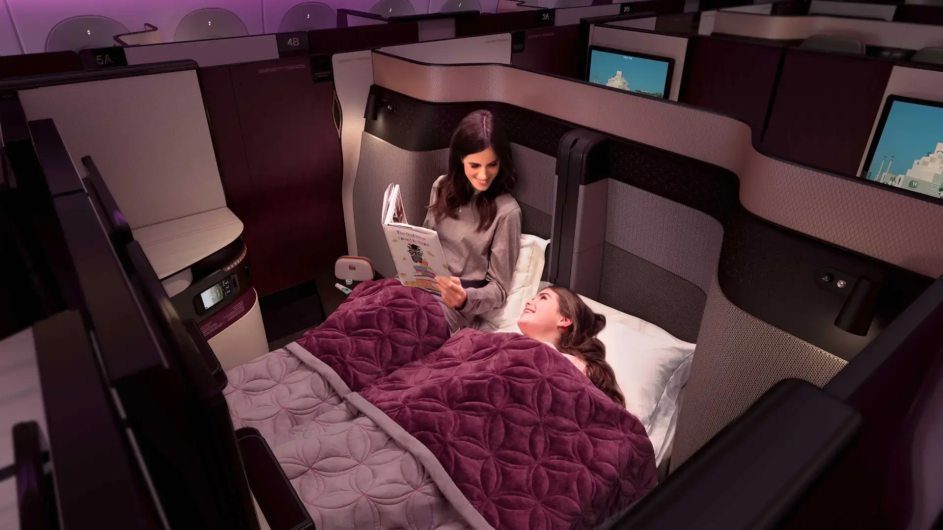 a mother reading bedtime stories to her daughter before going to sleep in Qatar Airways QSuite