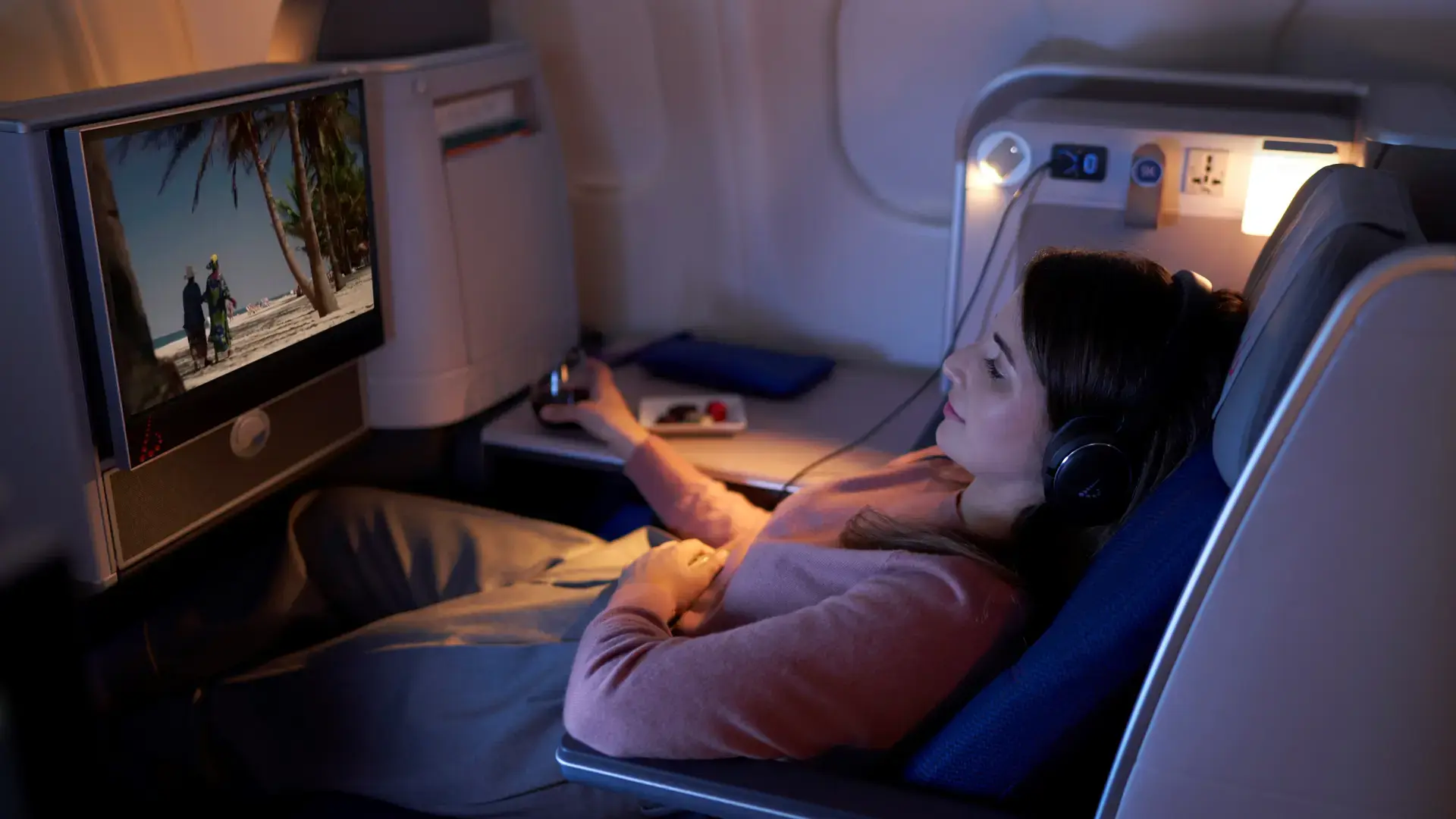 a woman sitting in business class cabin watching a movie