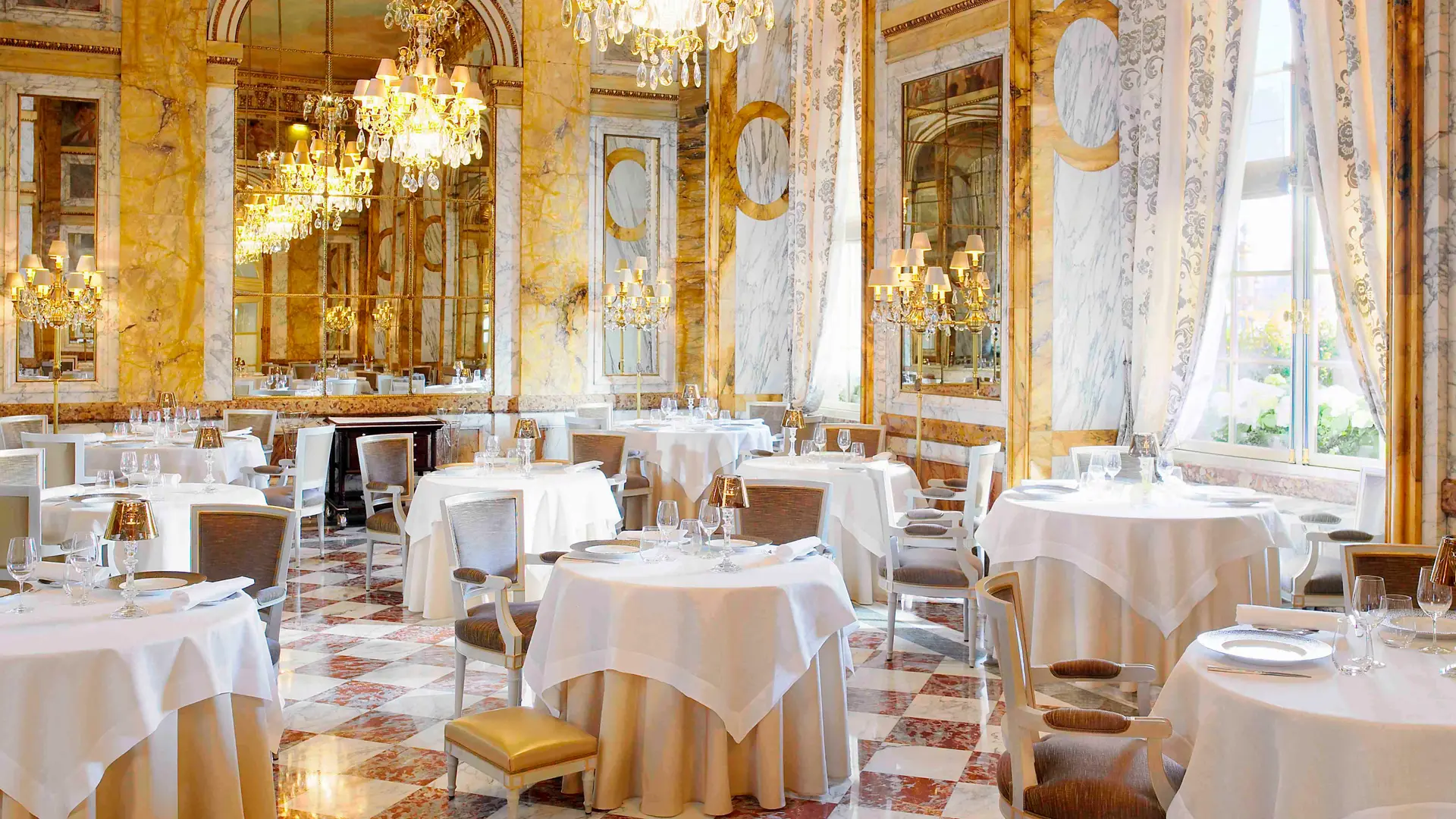 Golden marble walls, white tables, and patterned floor  at Les Ambassadeurs.