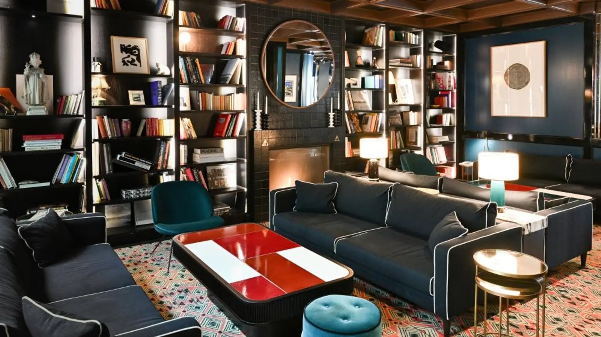 reading area at Le roch hotel & spa paris with black furniture, black wall and two black bookshelfs with many books