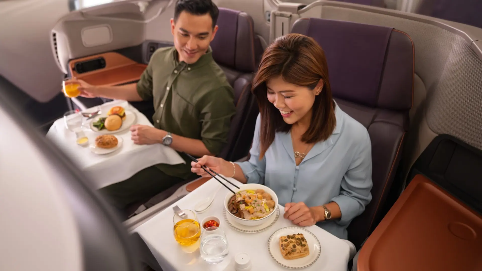 Happy asian couple enjoying a meal on a businessclass flight.