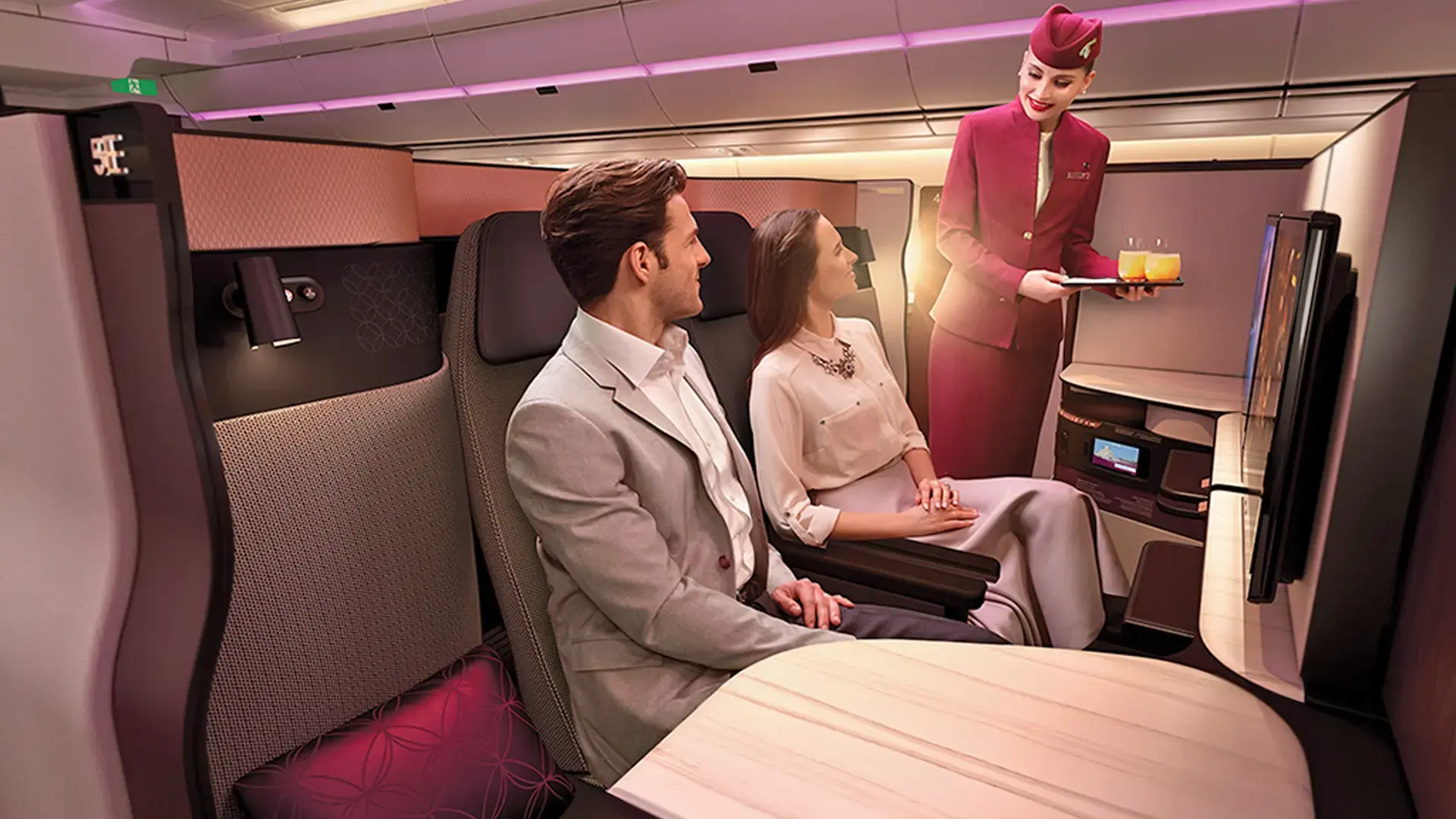 air hostess serving a couple juice in Qatar Airways business class