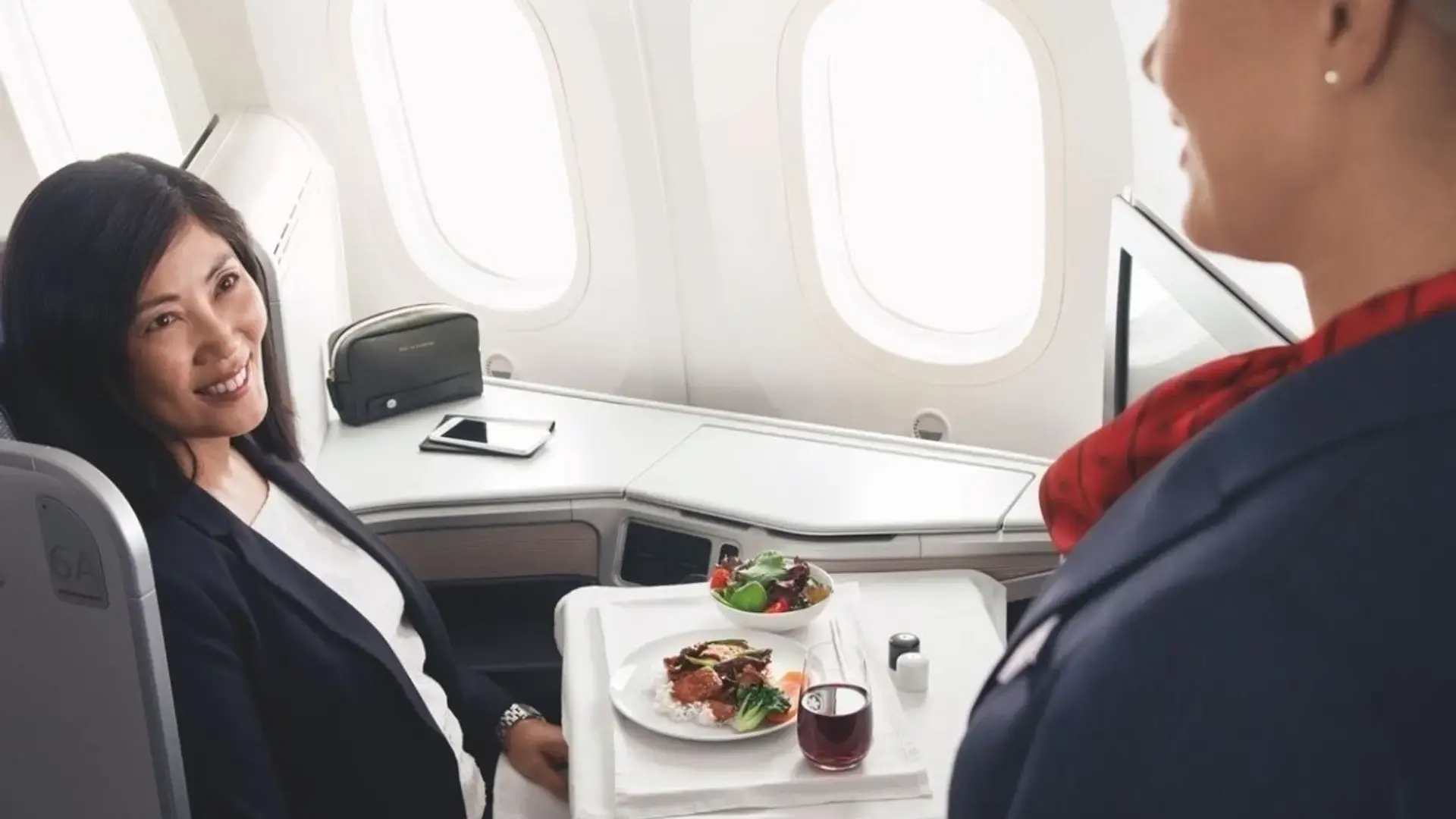 a woman getting her lunch served in the Air Canada business class cabin