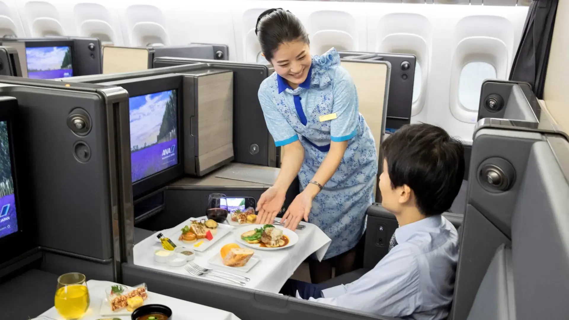 air hostess serving a male passenger food in the ANA business class