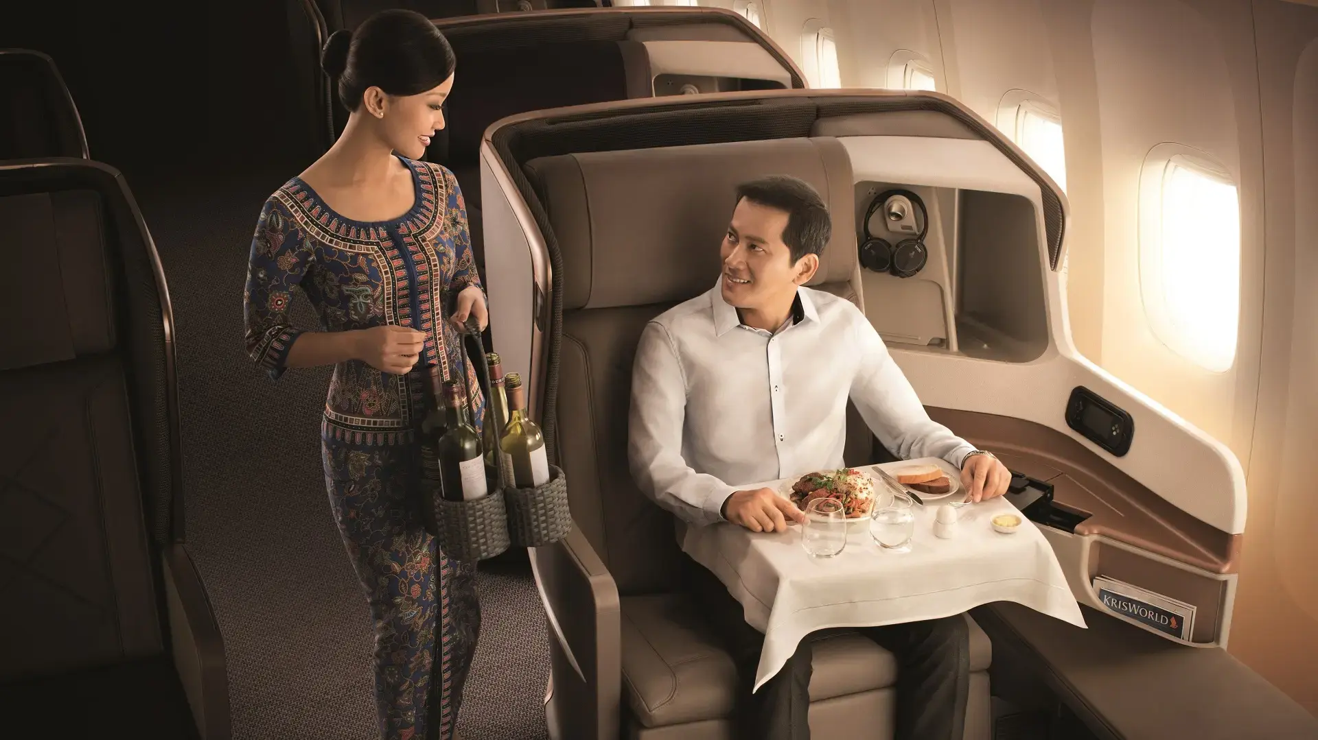 a passenger getting served in the Singapore Airlines business class by an air hostess