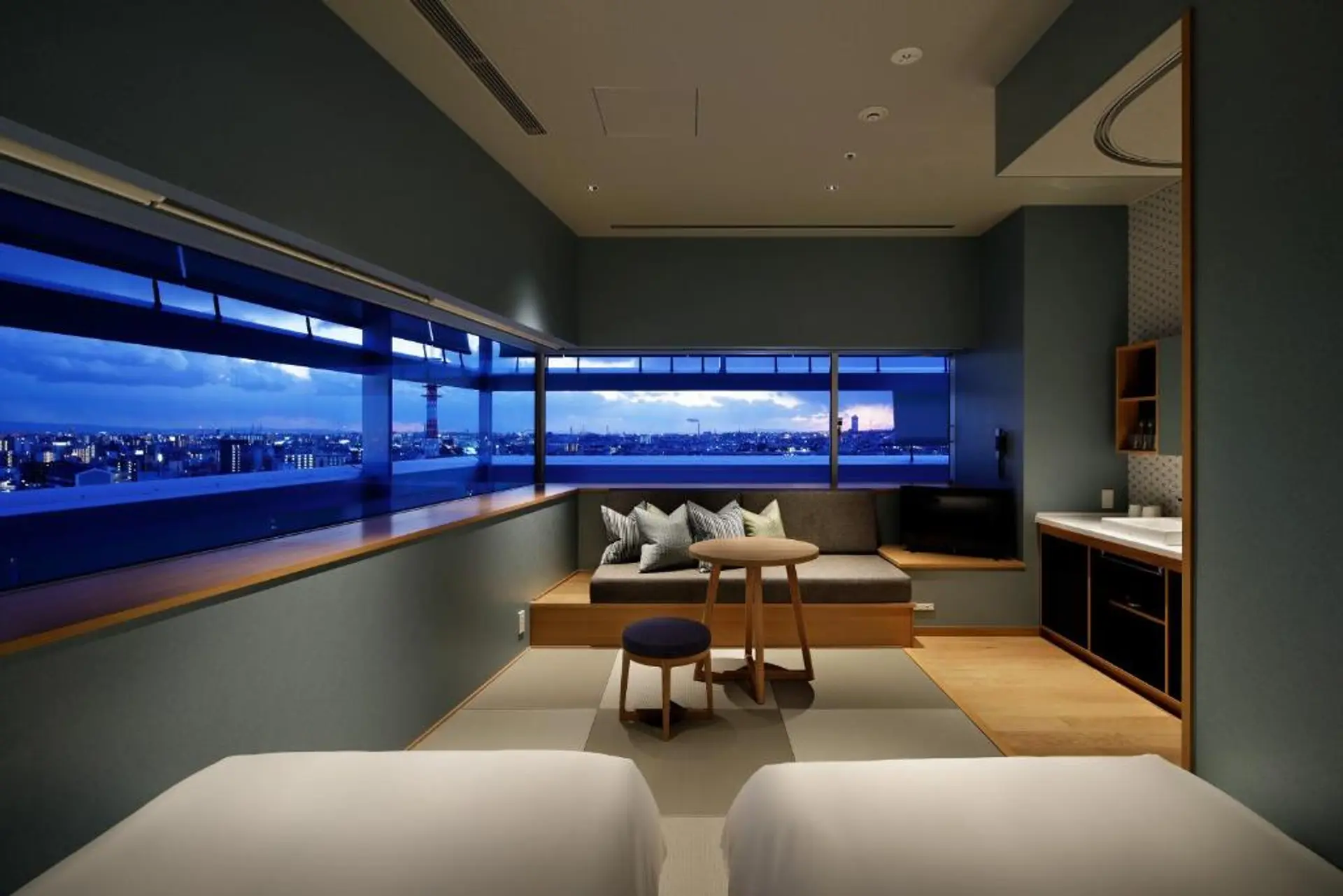 Hotel room, private kitchen, seating area with evening view of Osaka.