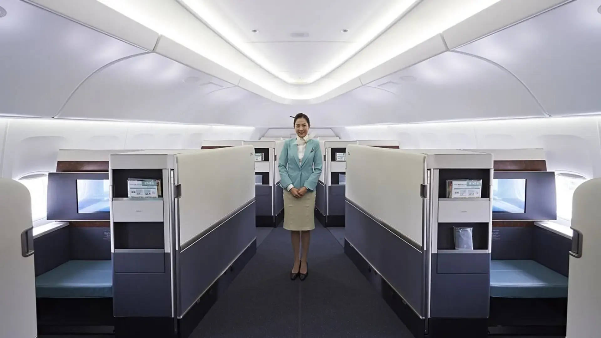 an air hostess standing in the middle of korean air first class 