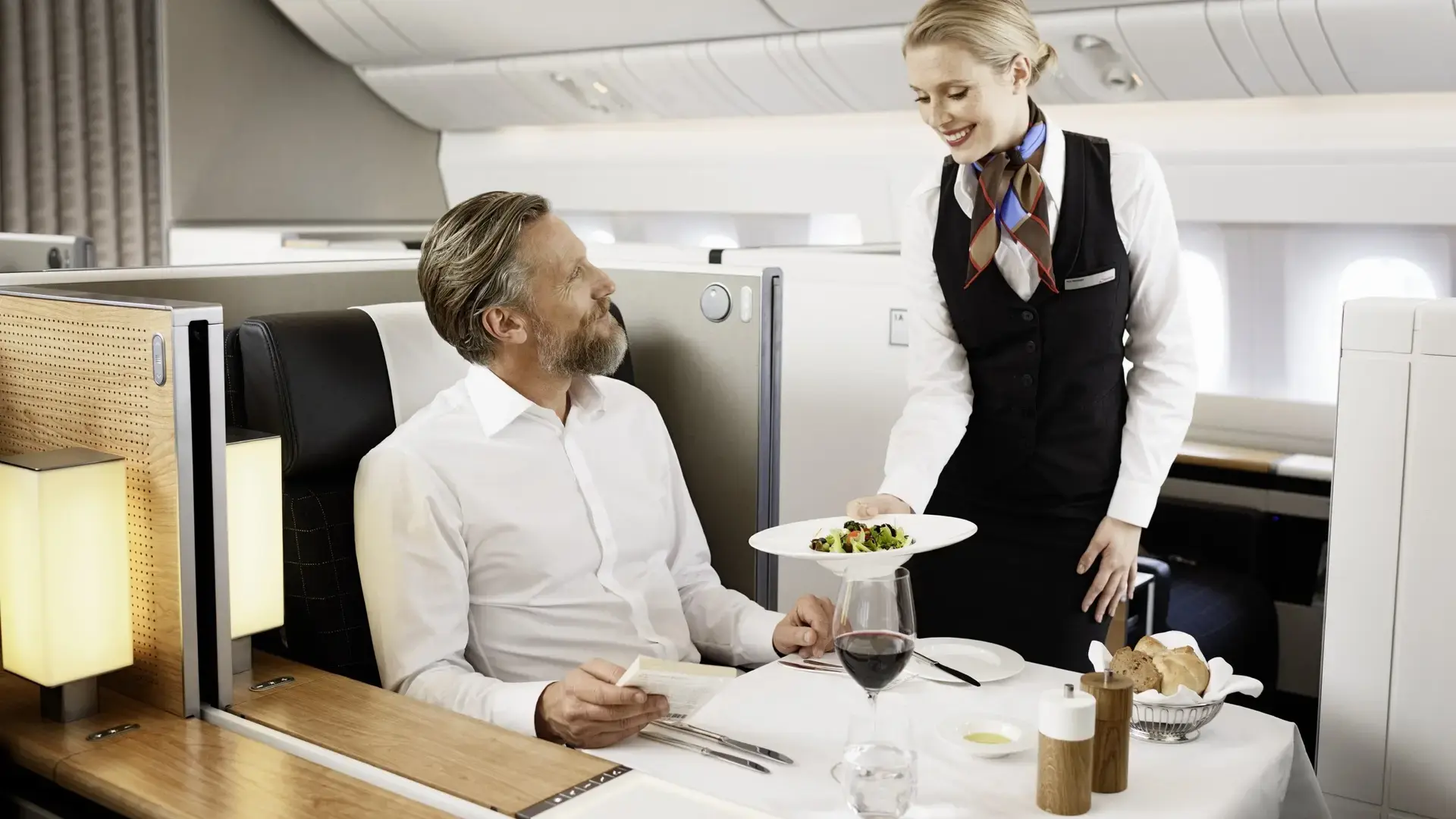 an air hostess serving a man in swiss first class