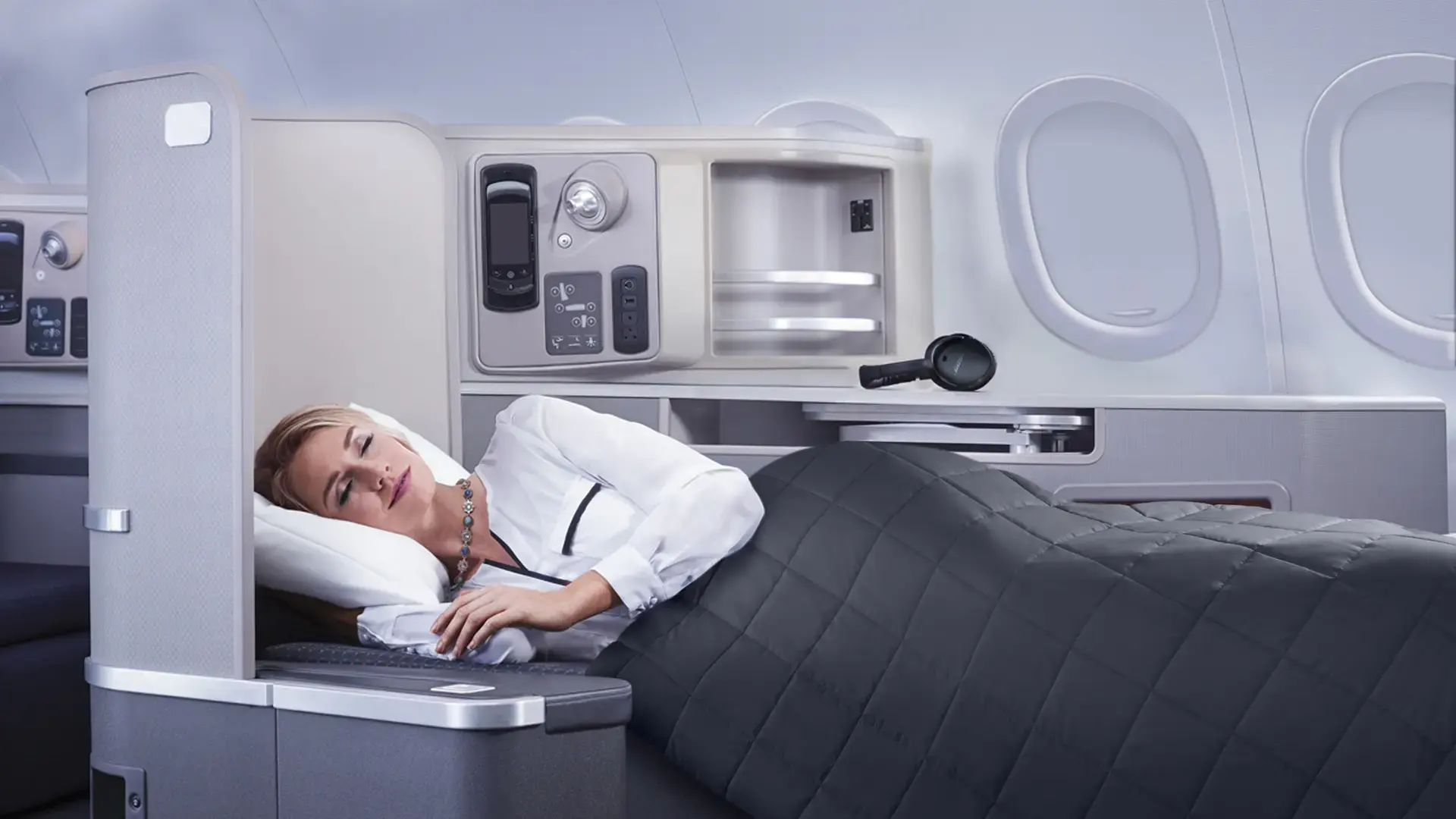 a woman sleeping in her american airlines first class bed
