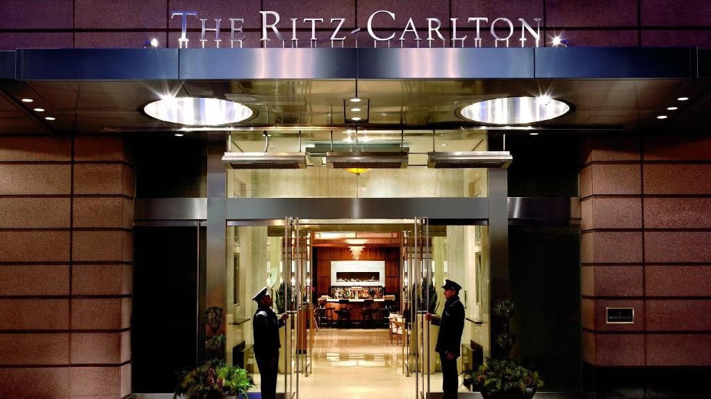 The ritz carlton boston main entrance with two  men holding up the glass doors.