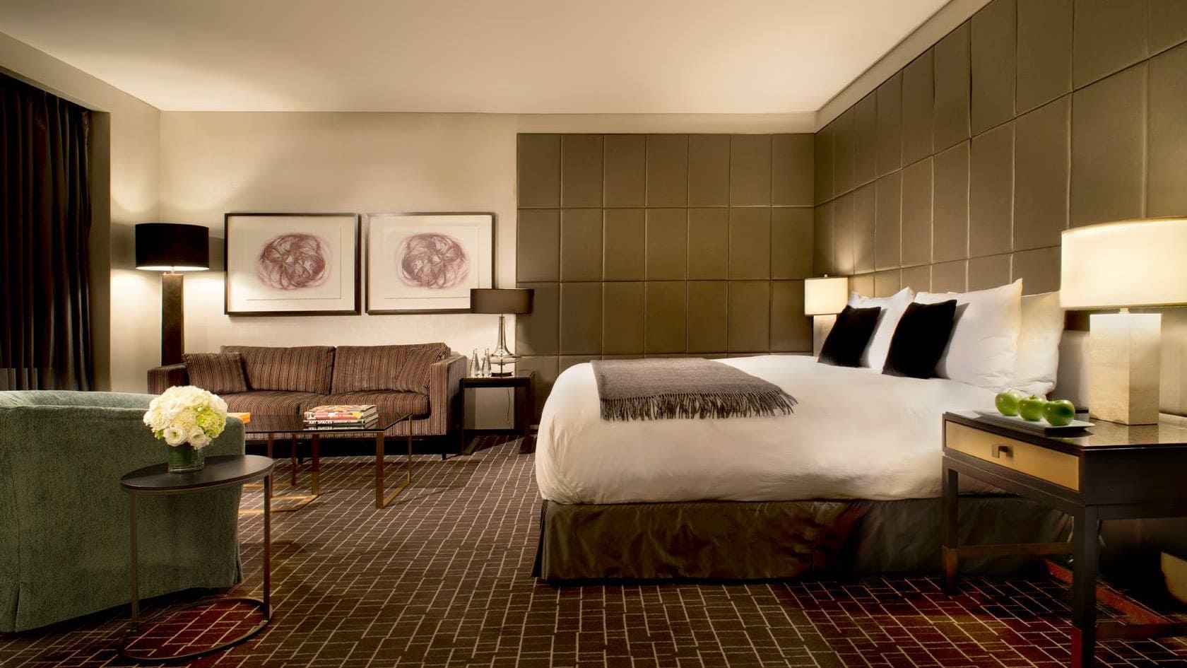 A suite at The hazelton hotel toronto with a king sized bed, black and white pillows and a sofa with two paintings above