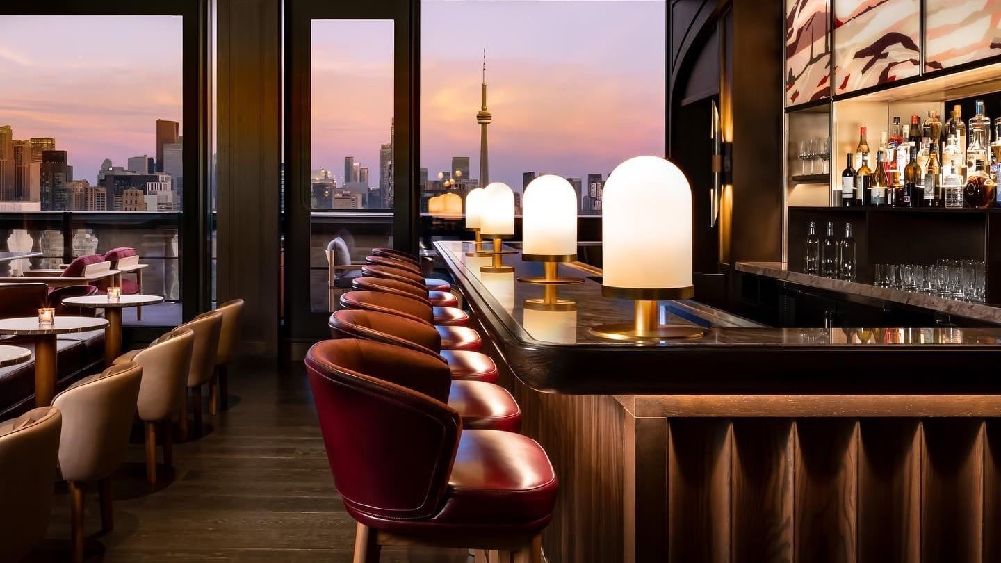 a resturant and bar at park hyatt toronto hotel with windows looking out over the city.