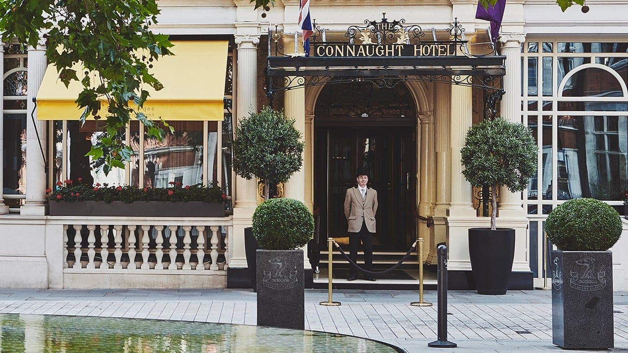 A hotel worker standing infront the connaught, london.
