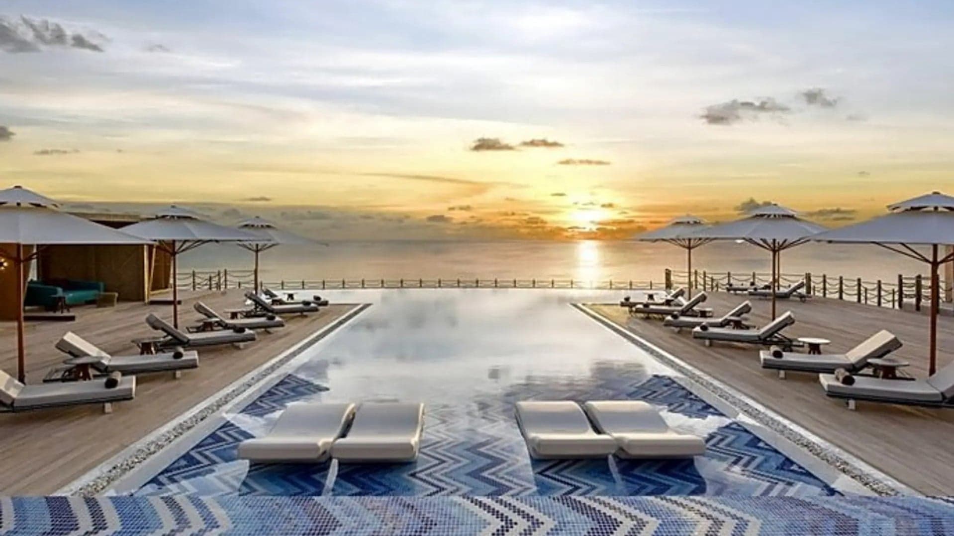 Infinity pool with sunbeds and the ocean at JW Marriott Maldives Resort å Spa.