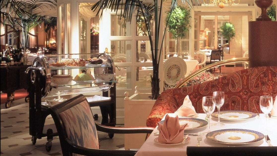 Dining area with orange sofa, black and patterned chair, and white decor.