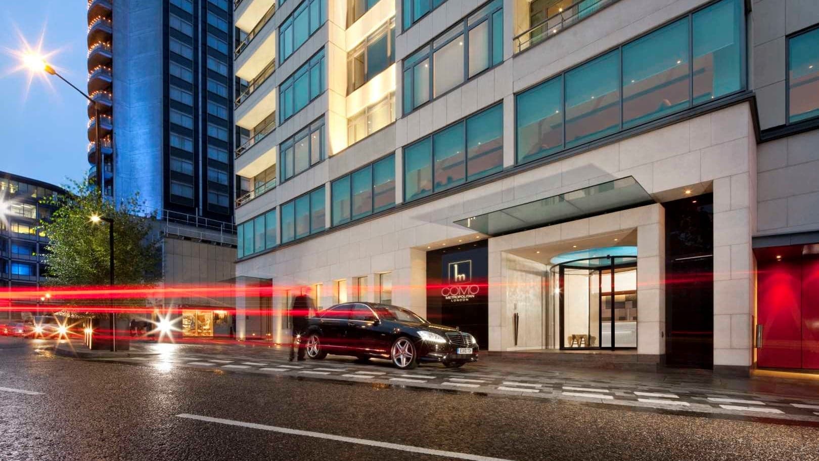 Front entrance of COMO Metropolitan London with a black car and a driver opening the door.