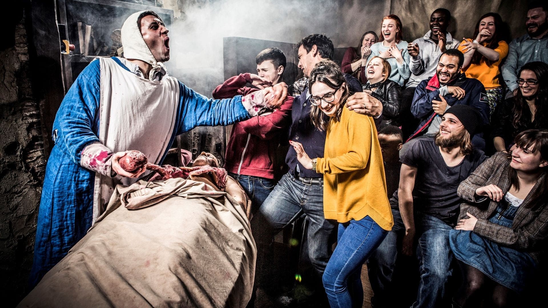 Man in classical doctor outfit taking out organs of a fake body, people smiling and disgusted, taken in The London Dungeon.