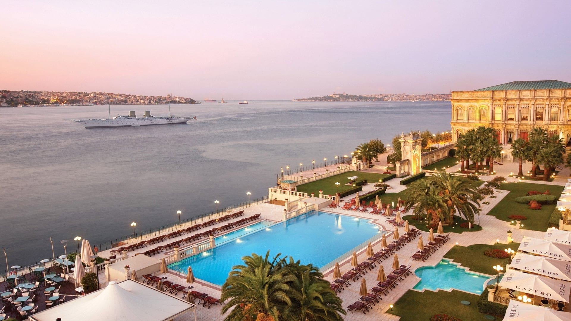 The majestic Çırağan Palace - Kempinski with view of the private pool area offering a view of the Asian coast and it's grandeur hotel building with it's royal heritage