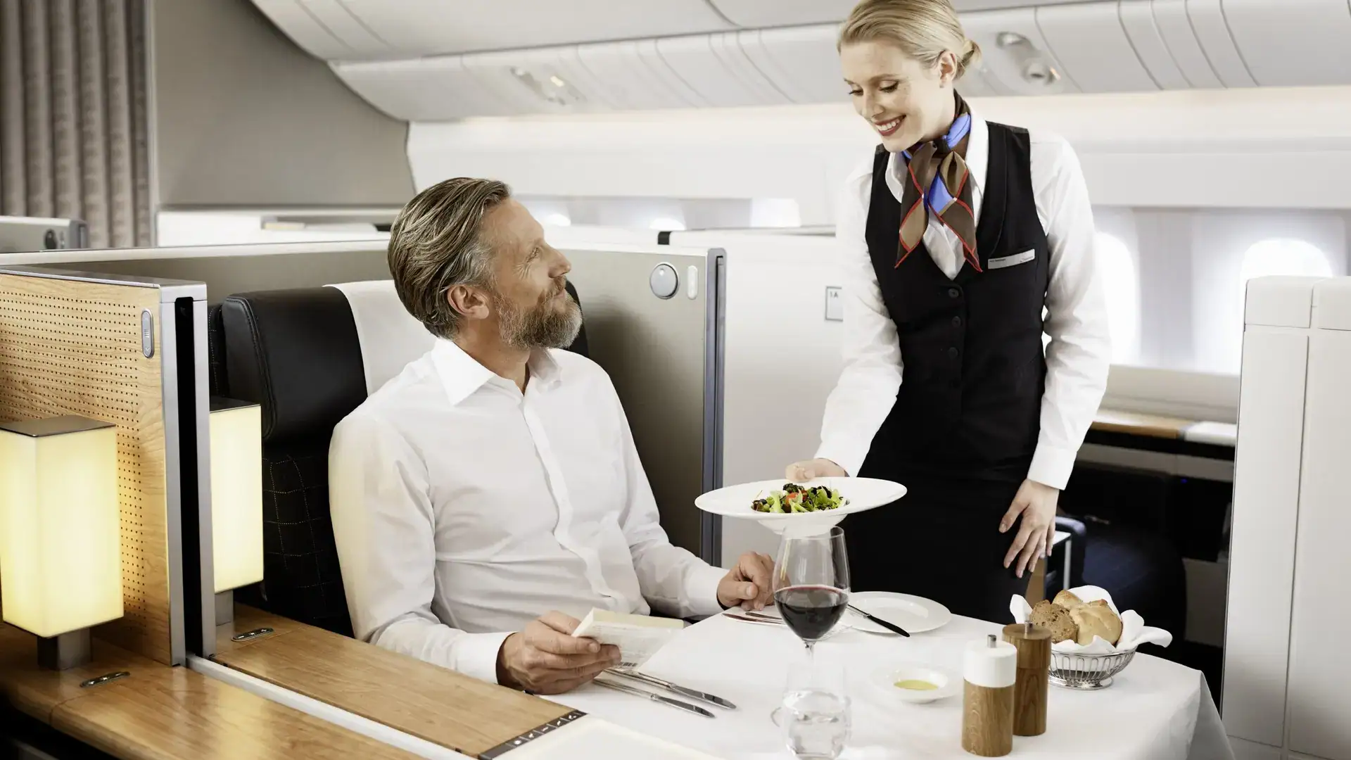 an air hostess serving a man in swiss first class