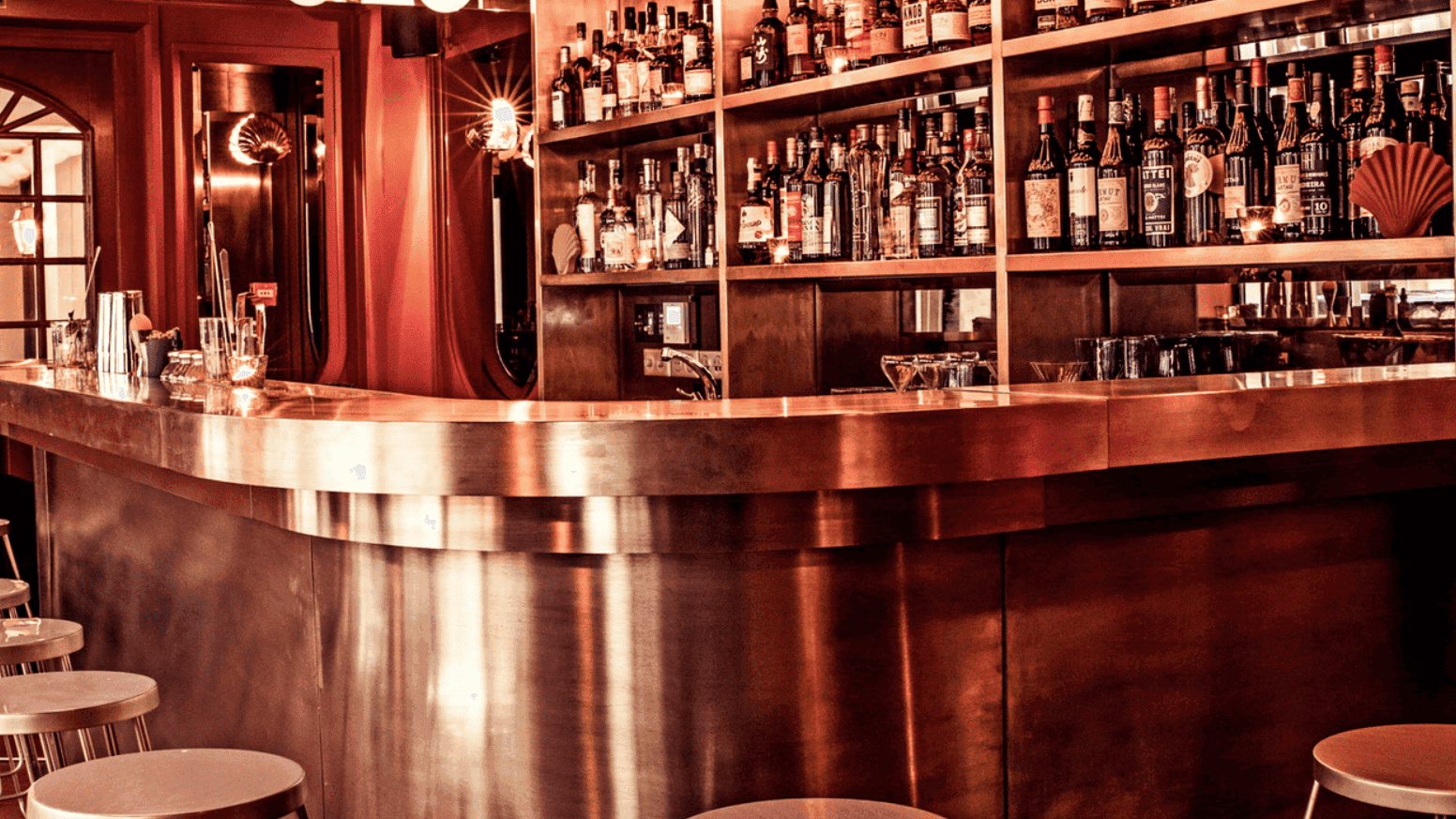 Rose metal coloured bar area with drinks and seating area.