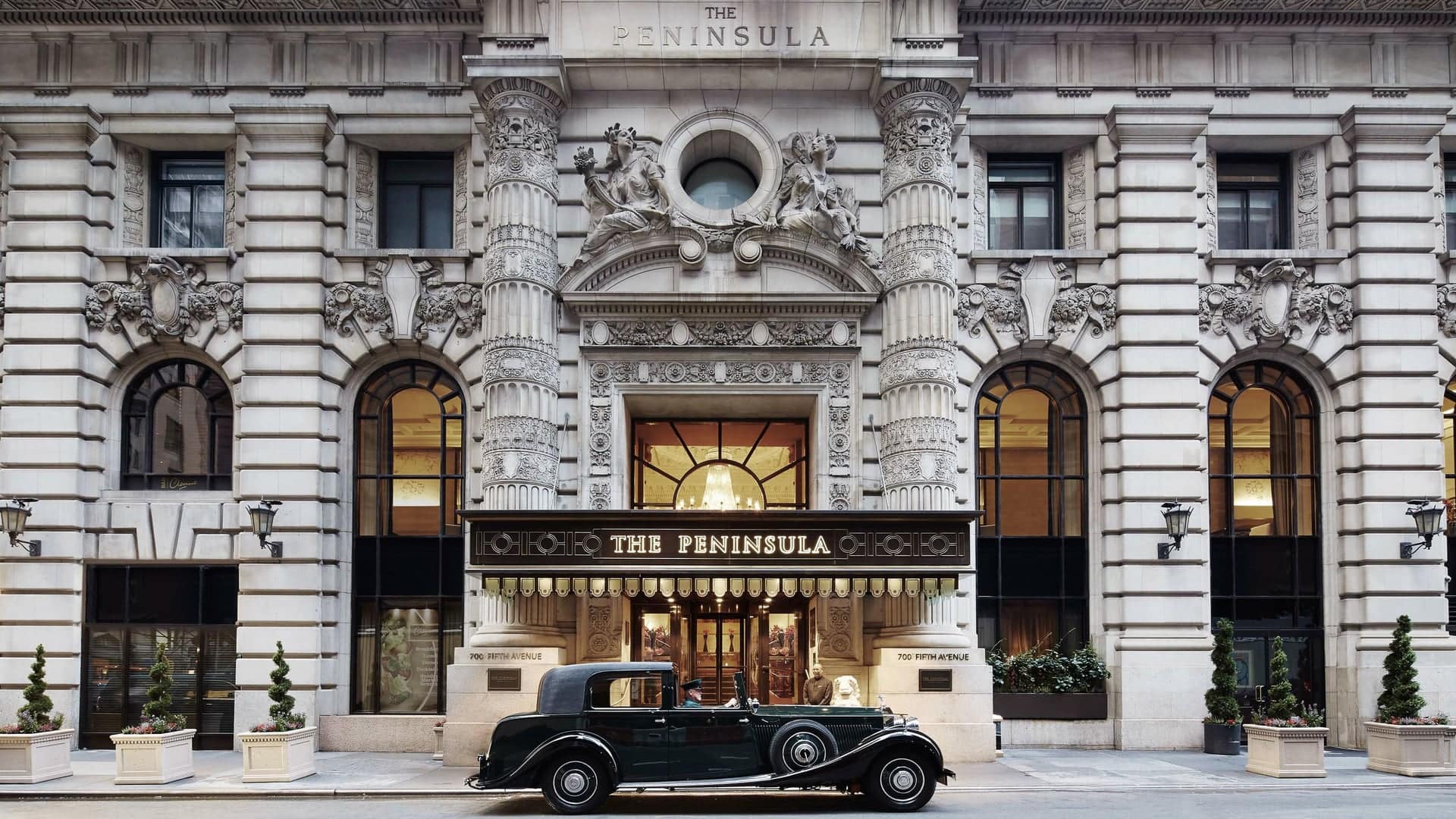 Main entrance of The Peninsula New York with a black car parked in front