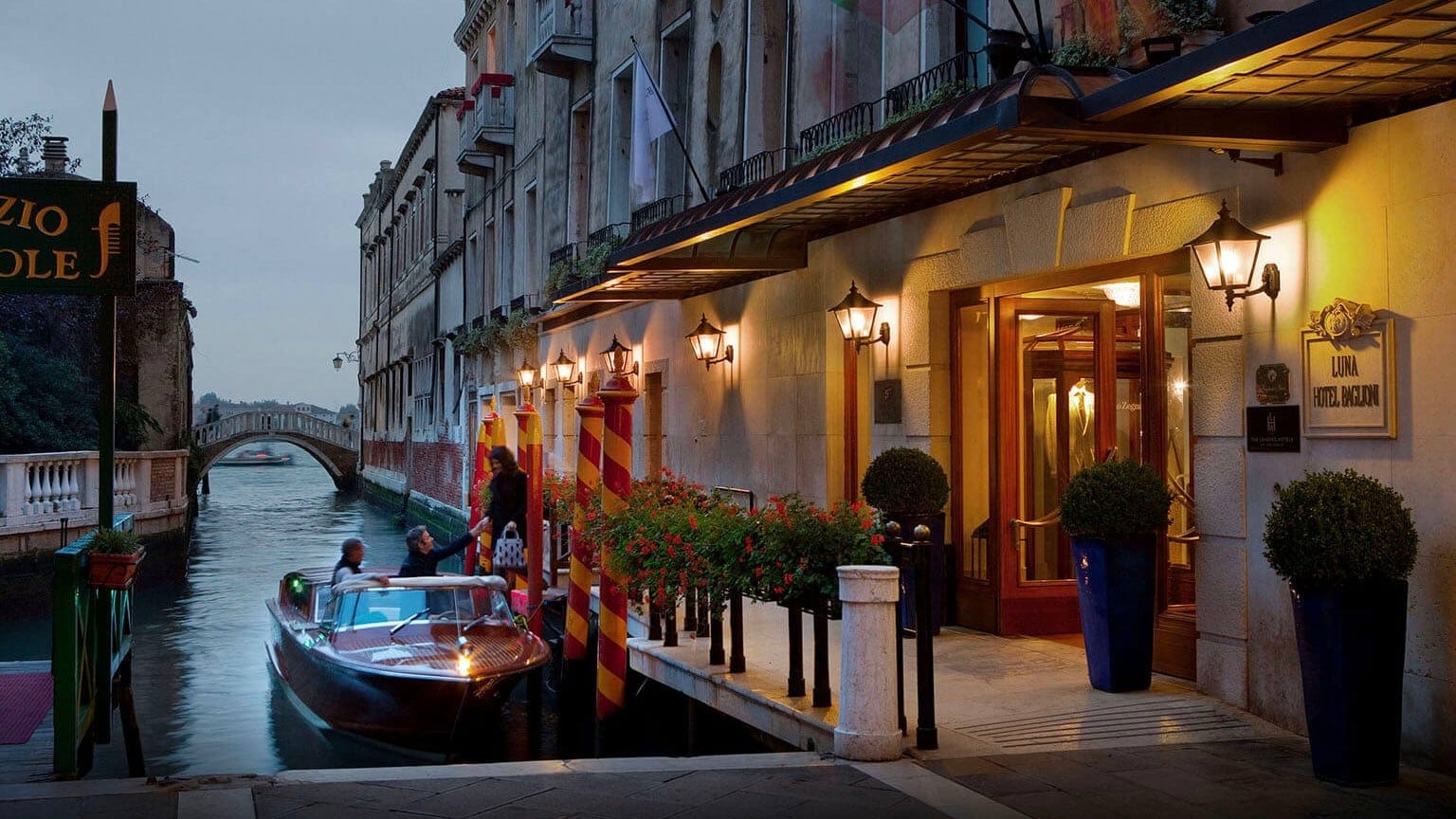 People hopping on a boat outside Baglioni Hotel Luna at evening time