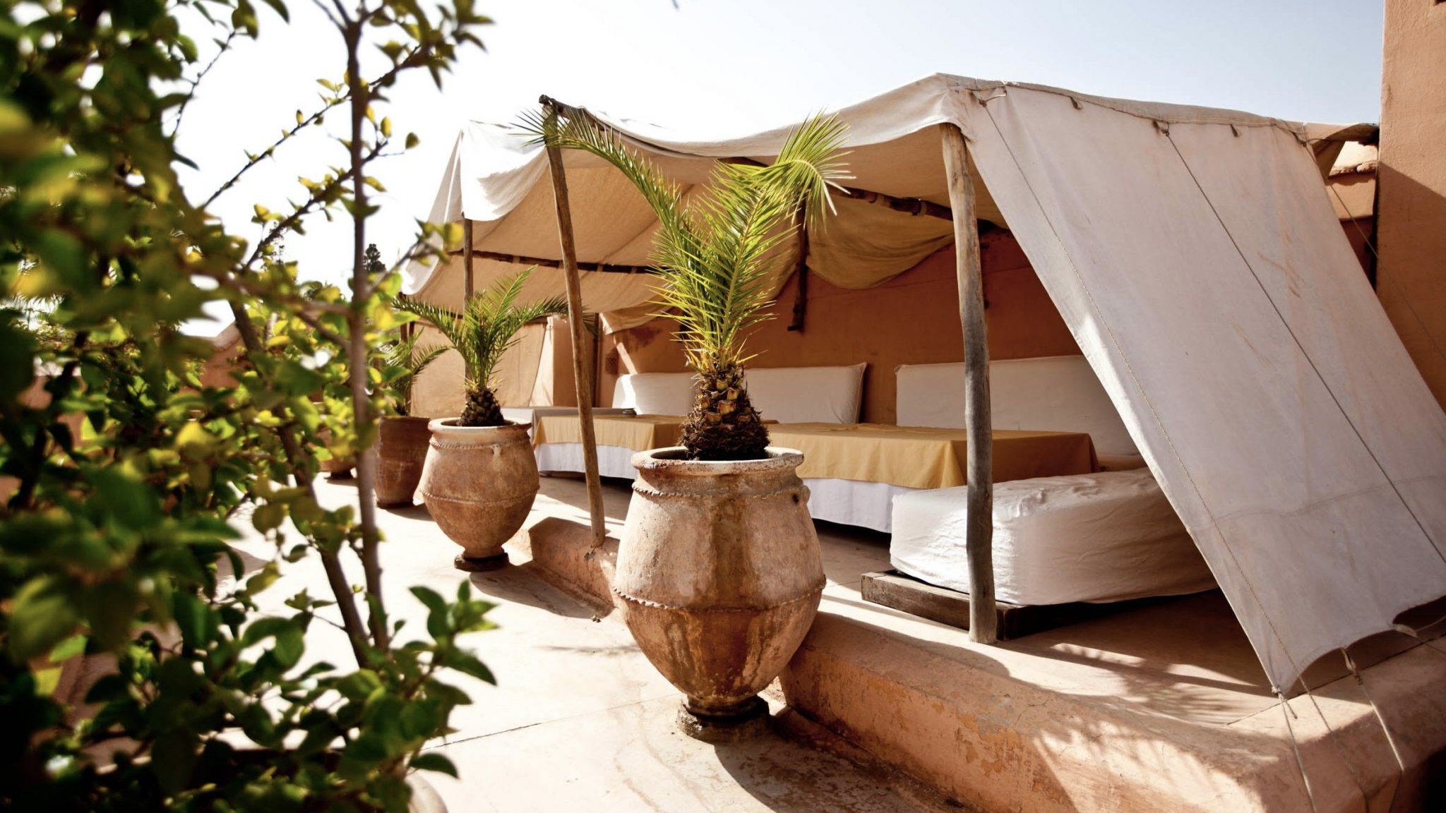 Sitting area with a white tent inspired roof and orange vases that match the sitting area