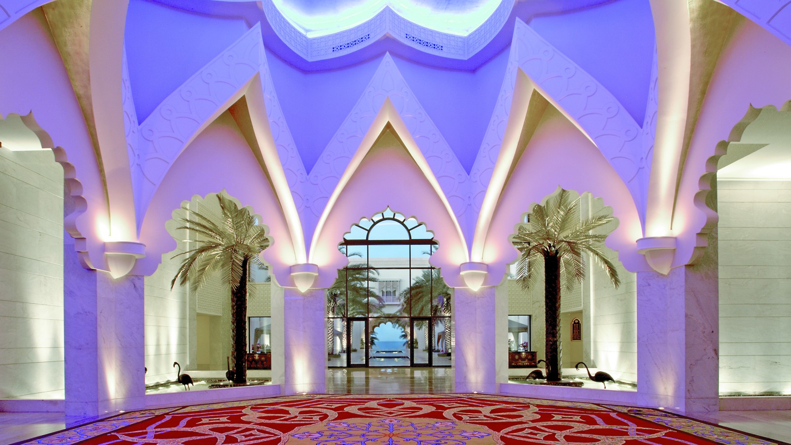 Red, yellow and blue pattern floor with flowers in the median, tall white marble walls and a view to the ocean
