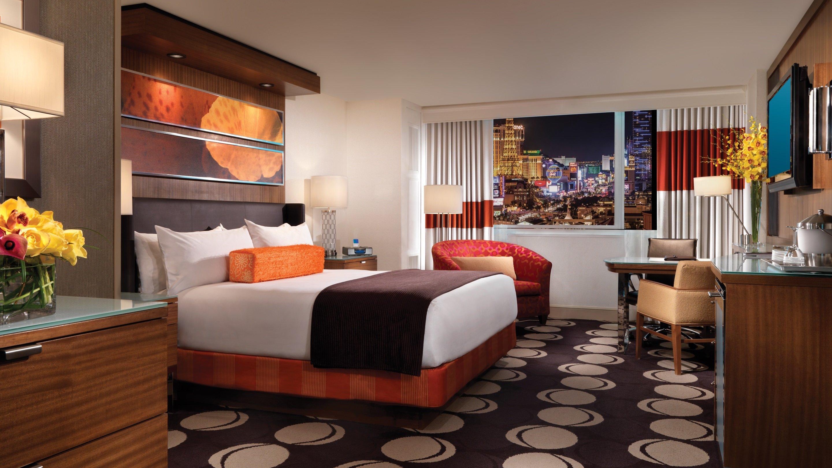 Hotel room with pattern carpet, window to Las Vegas, red chair, and a colourful room.