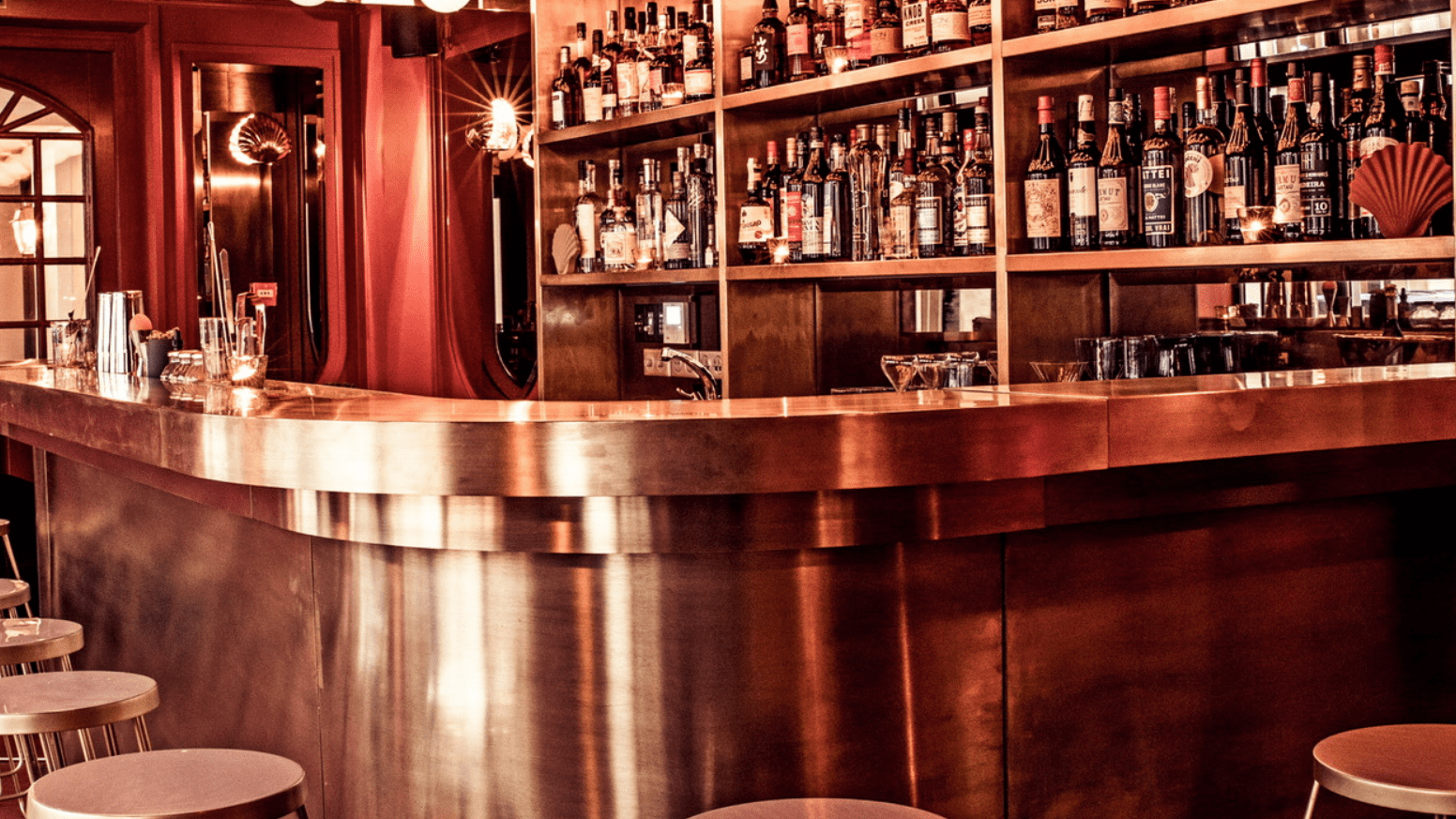 Rose metal coloured bar area with drinks and seating area.