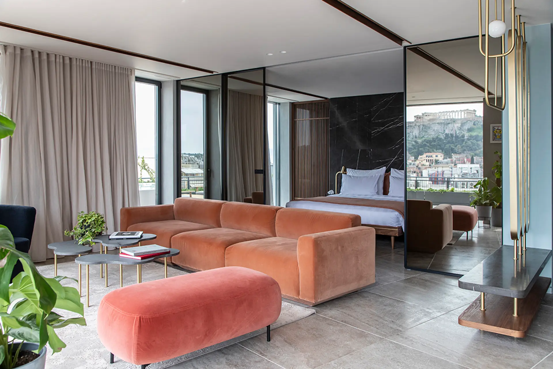 Hotel room of Perianth Hotel with red and orange furniture, kingsize bed in white, dark grey floor, and view of Athens