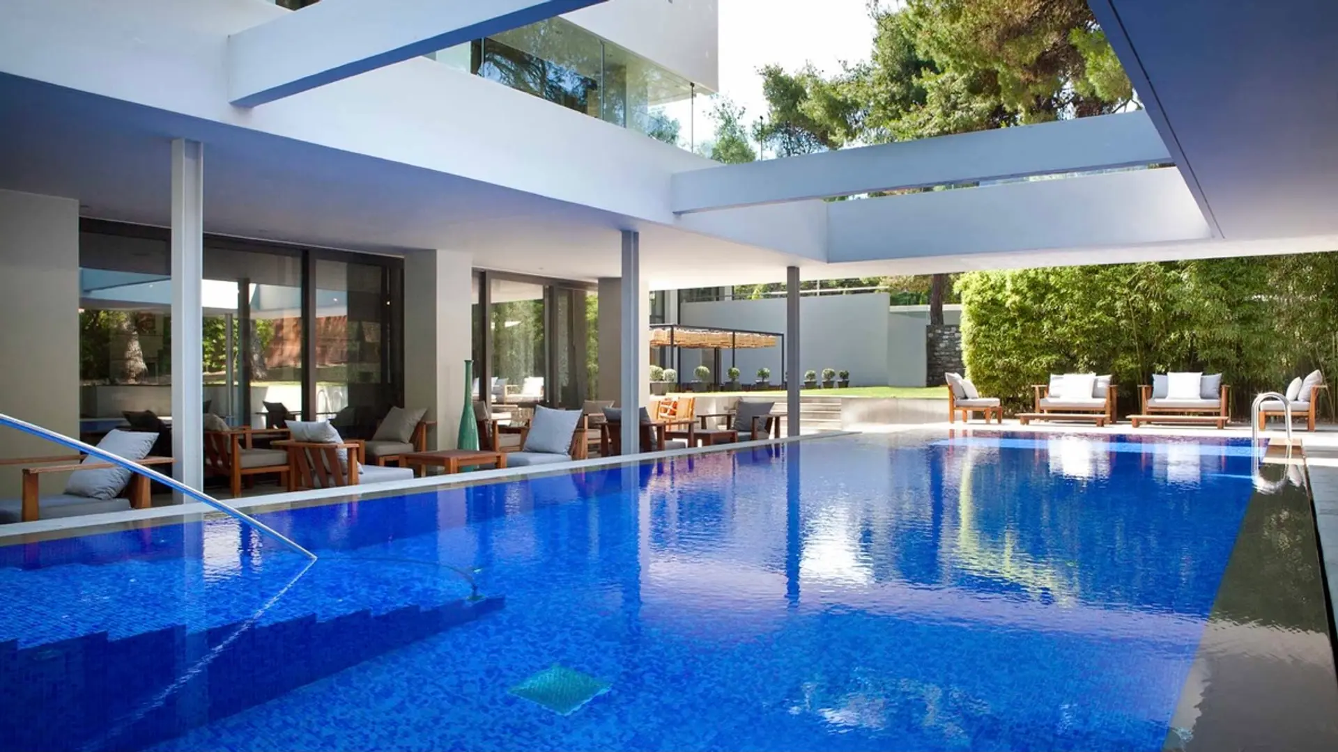 Pool area with open roof, white decor and sunbeds