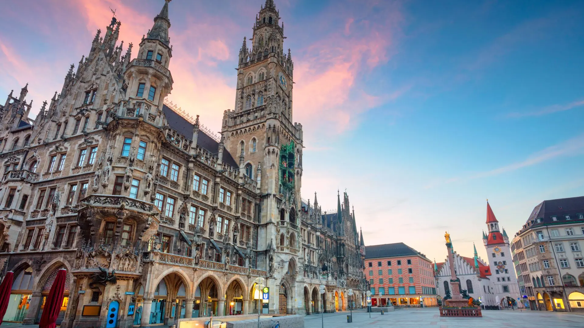 A large building in Munich, Germany with a stone design and beautiful sunset behind.