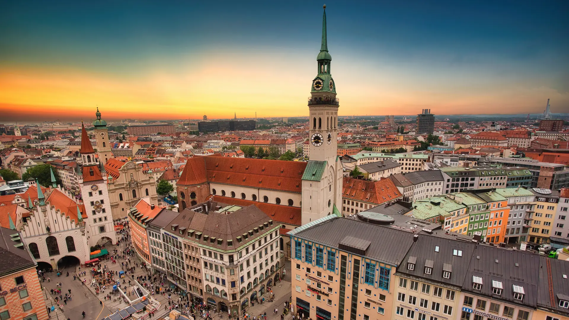 Bird view of Munich, Germany. Large buildings, people walking on the street and a colourful sunset and arcitechture.