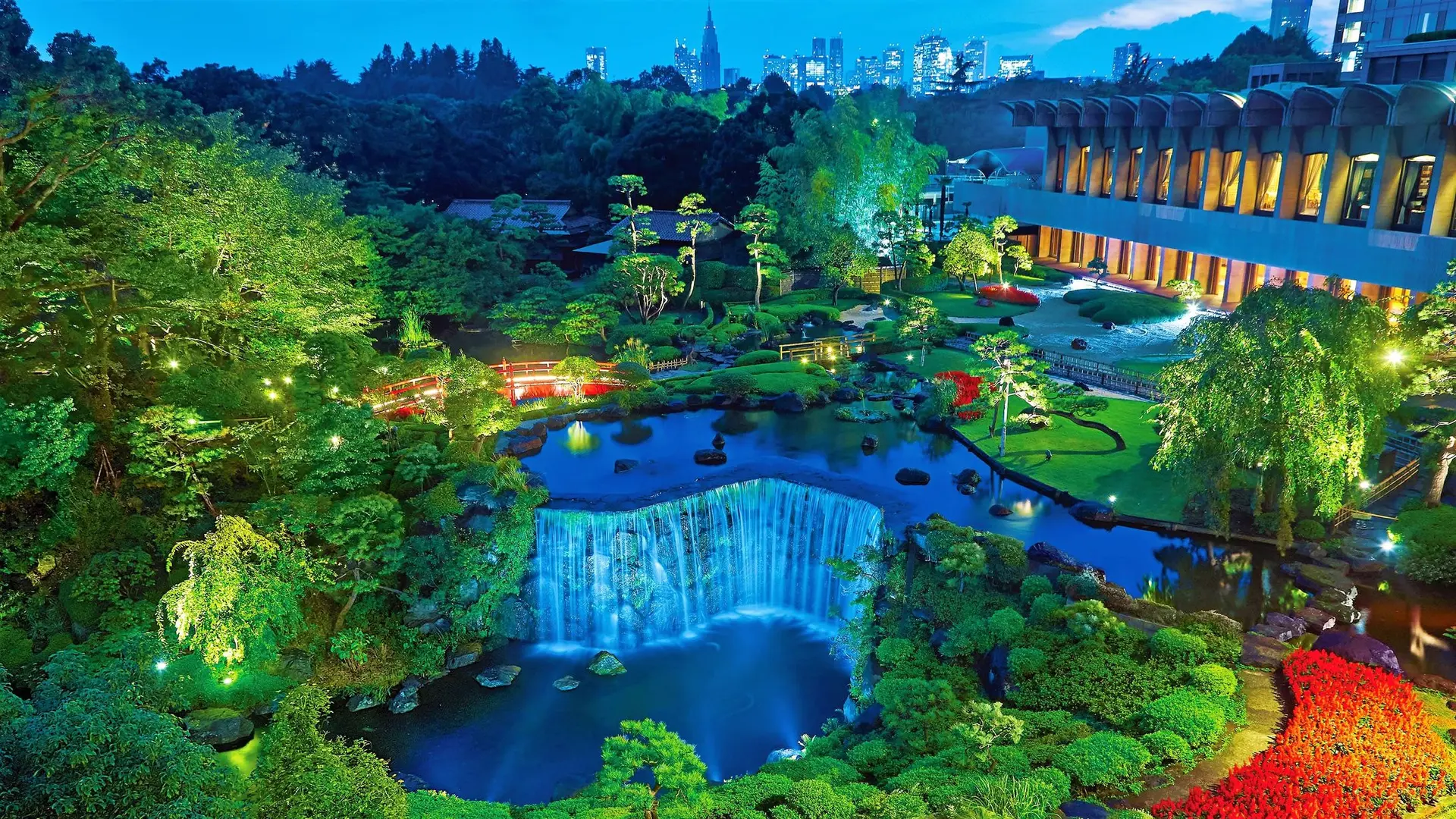 Unbeliveable garden with waterdall, tropical trees, red bridges and large white hotel at New Otani, Tokyo.