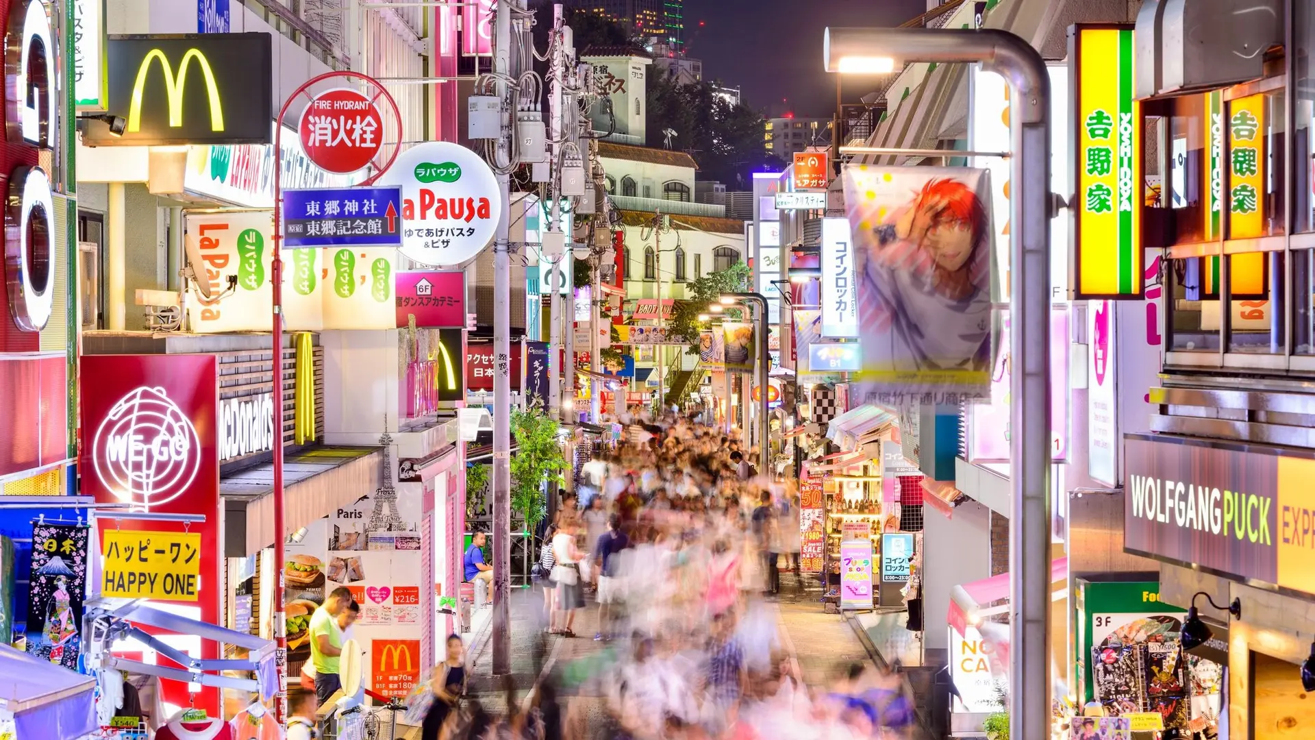 Harajuku with advertisements, crowded population and bright lights.